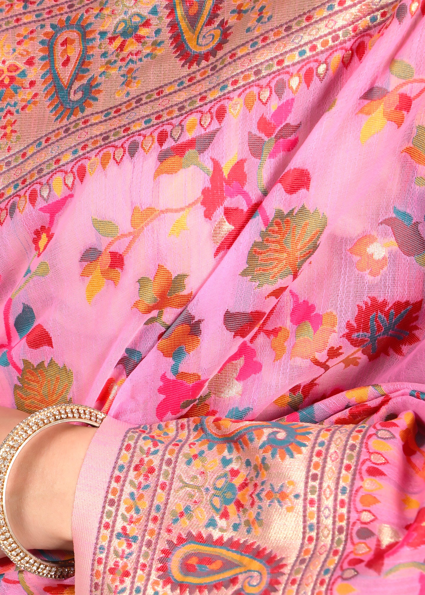 Close-up of the pink saree fabric highlighting its vibrant floral patterns and golden embroidered borders