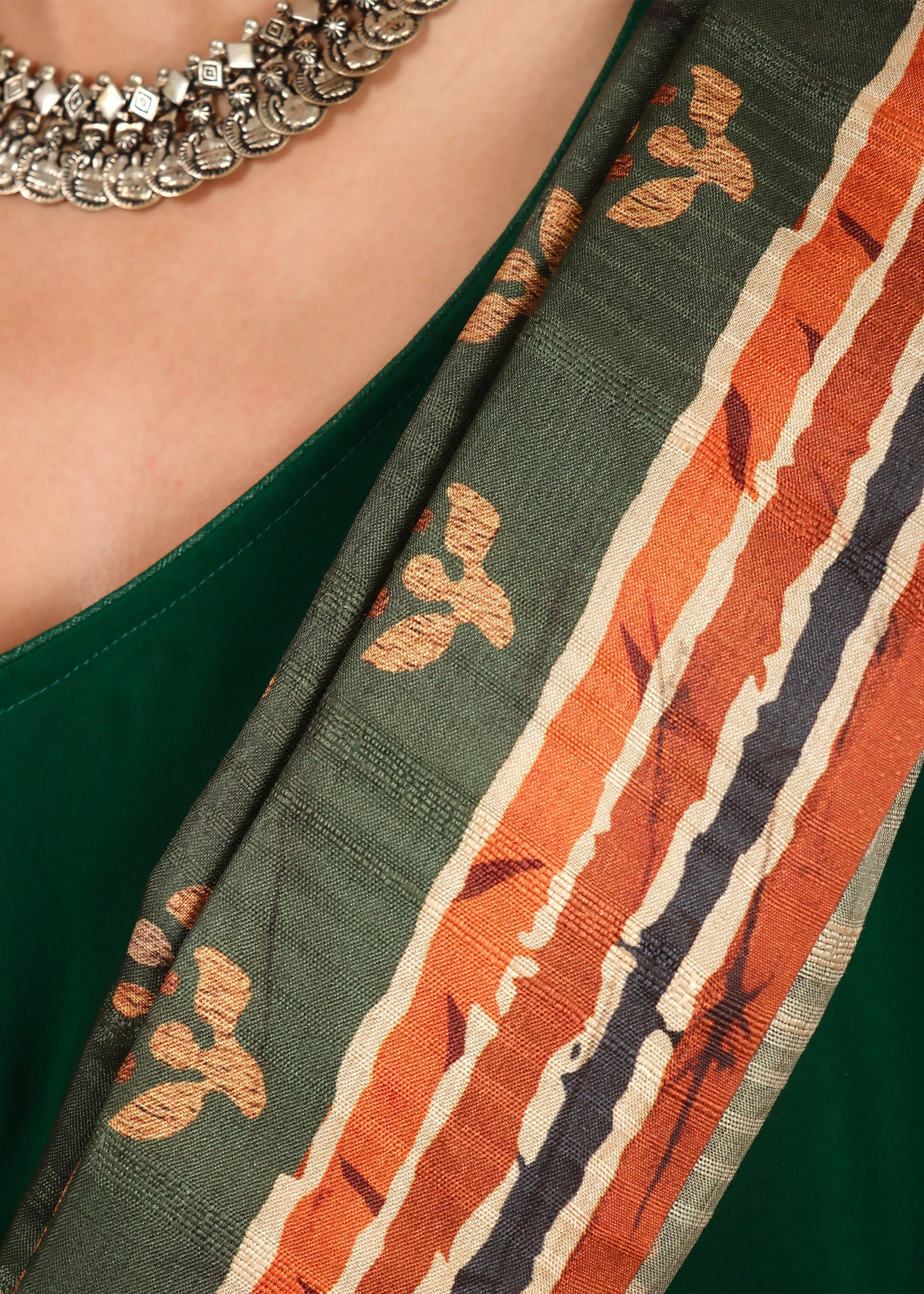 Close-up of the green saree's intricate golden motif design with red and white border details