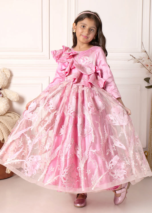 Child model twirling in a pink princess-style gown with floral embroidery and intricate lace patterns.