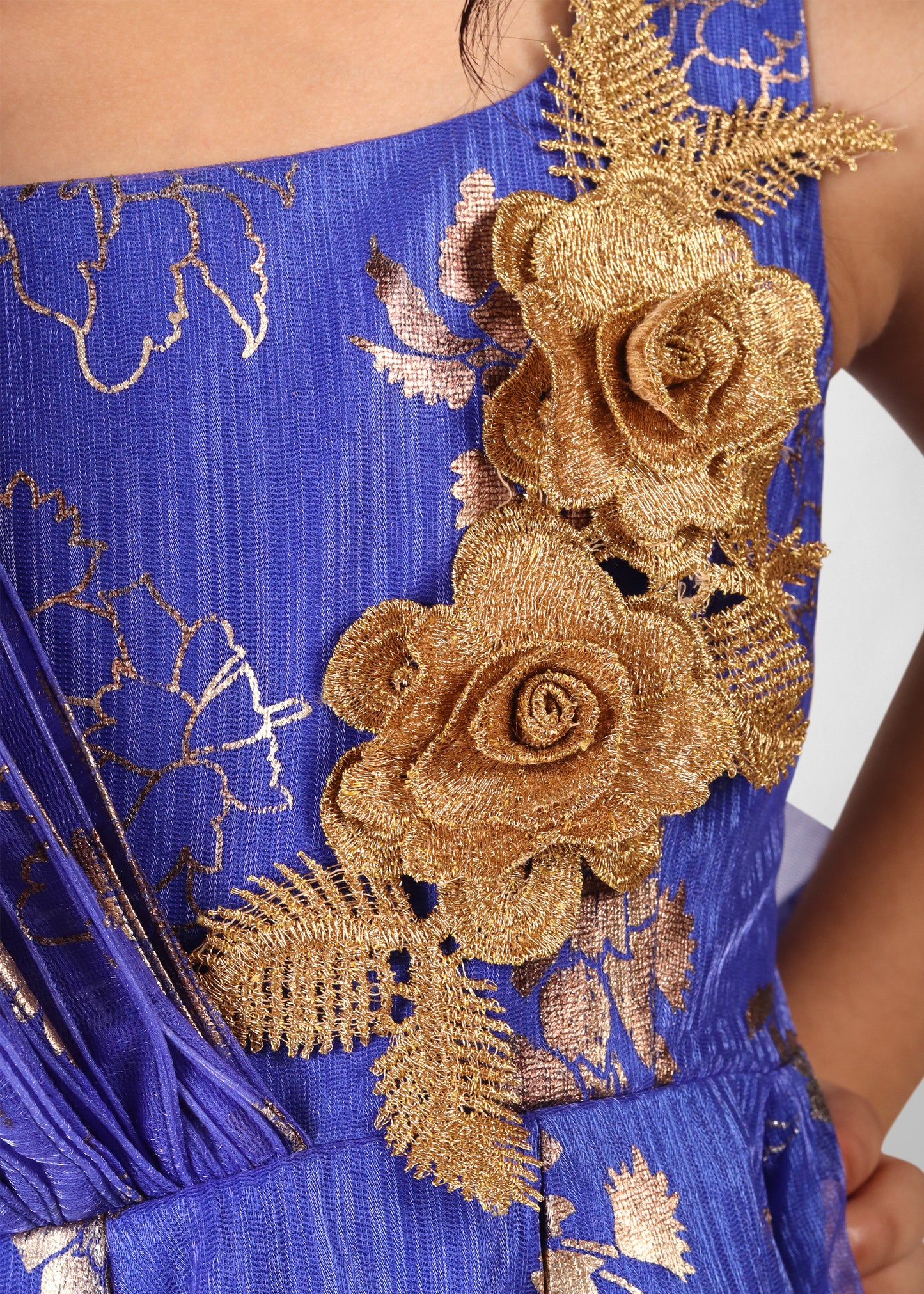 Close-up of intricate gold floral embroidery on a blue gown, highlighting the fine craftsmanship and detailing