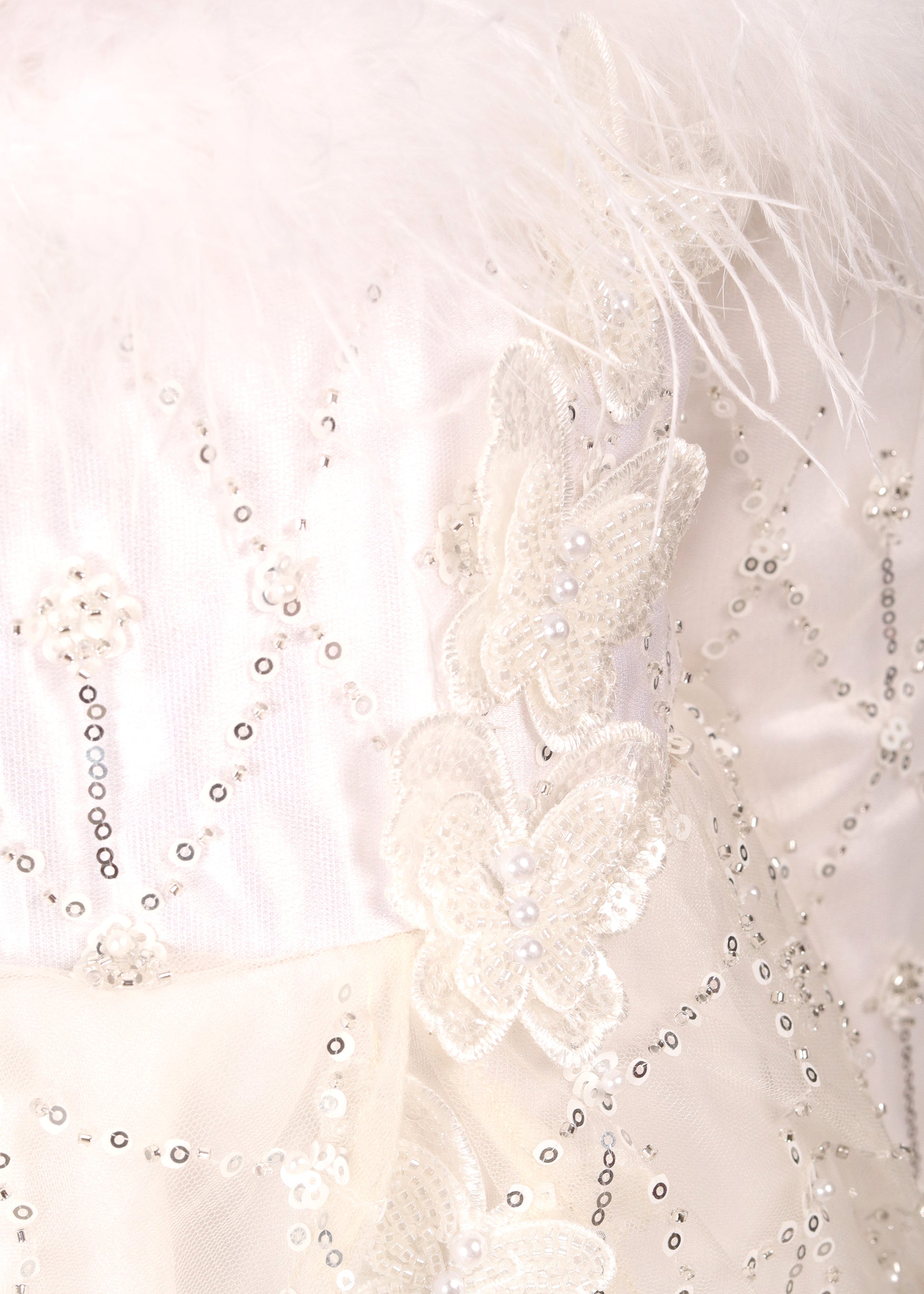 Close-up shot of the intricate butterfly and sequin embellishments on a white gown, highlighting the delicate details.