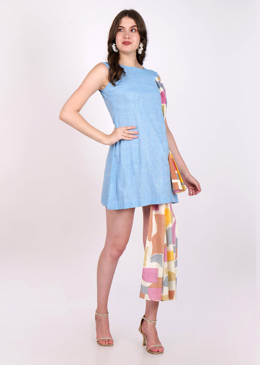 Front view of a light blue sleeveless mini dress featuring playful cutouts and a flowing colorful drape detail, worn by a model in white earrings and gold heels.