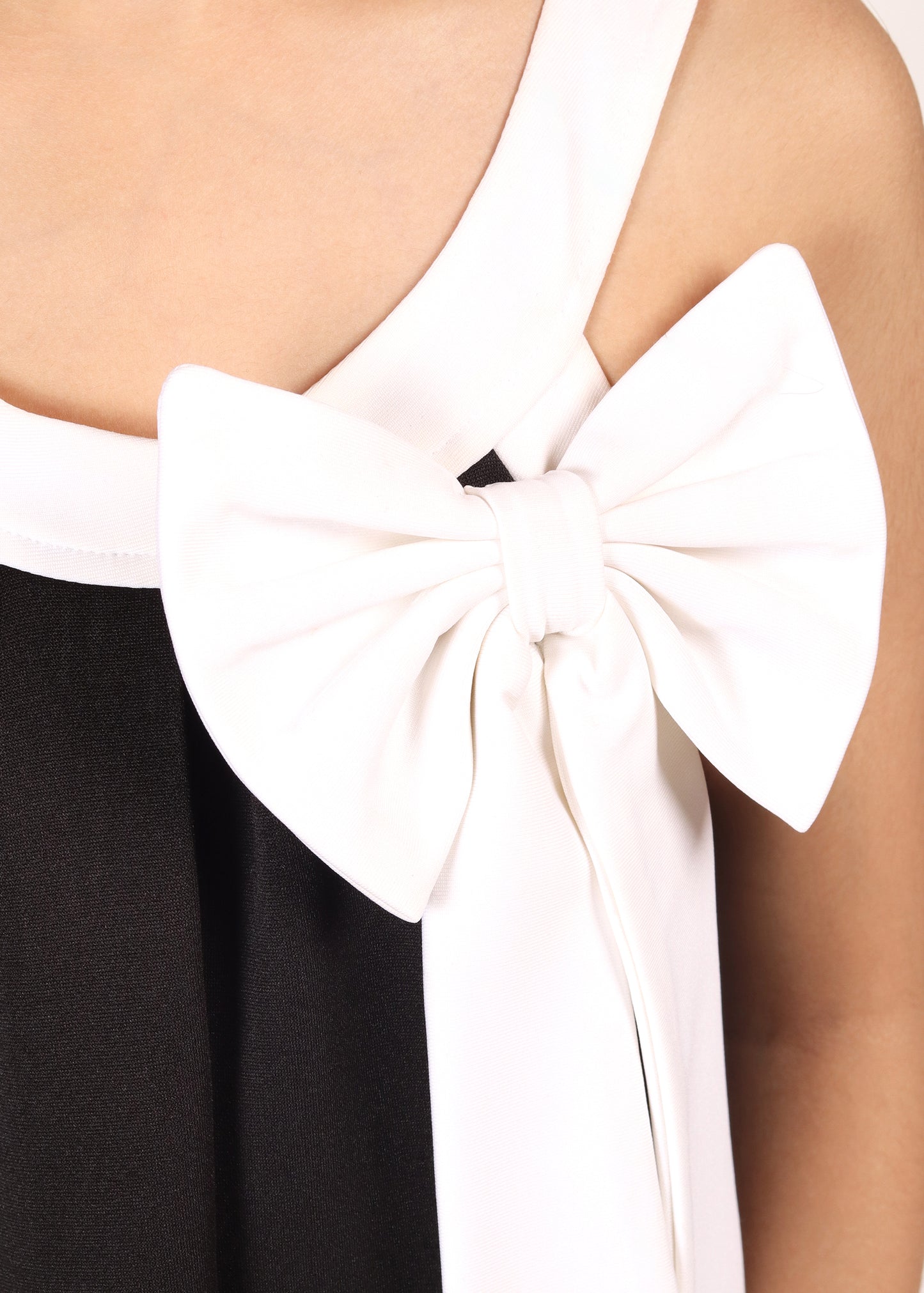 Close-up of a black dress with a white bow on the neckline, highlighting elegant contrast details