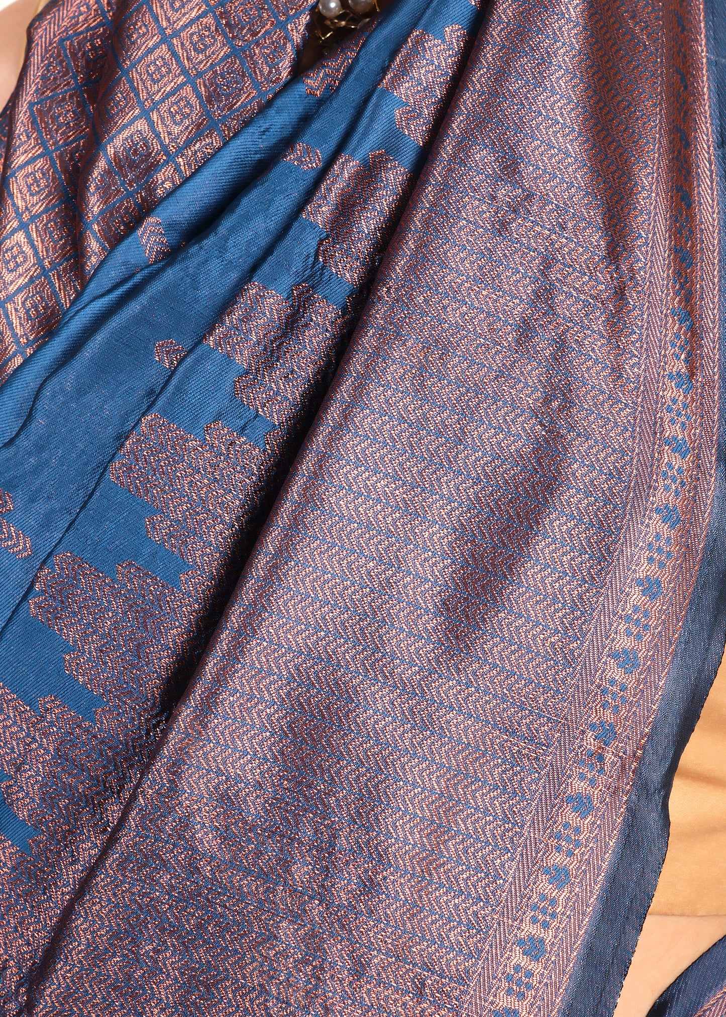 Close-up shot of copper zari motifs on royal blue silk saree, highlighting the detailed craftsmanship