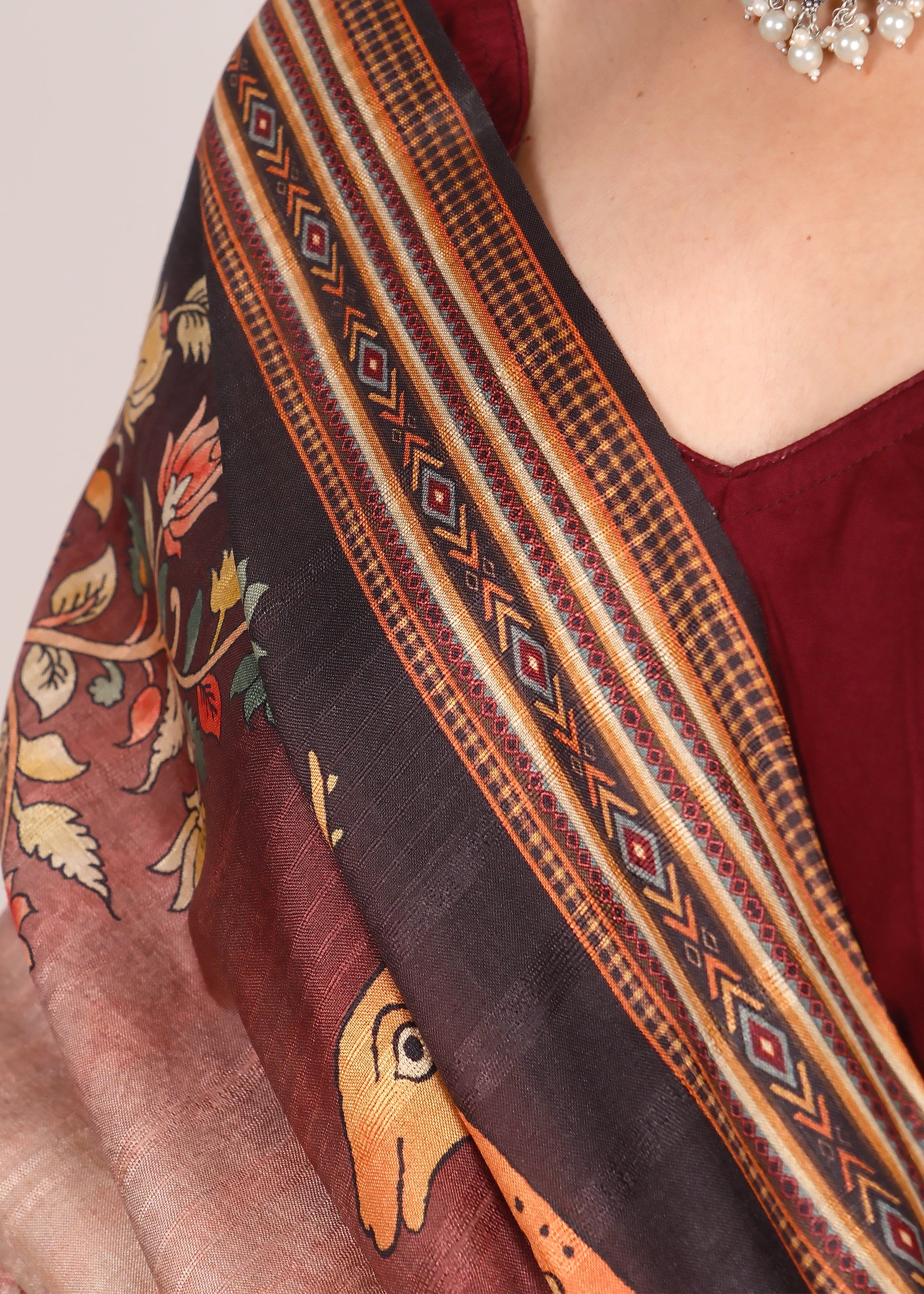 Close-up of a beige saree border showcasing detailed floral patterns and geometric stripes