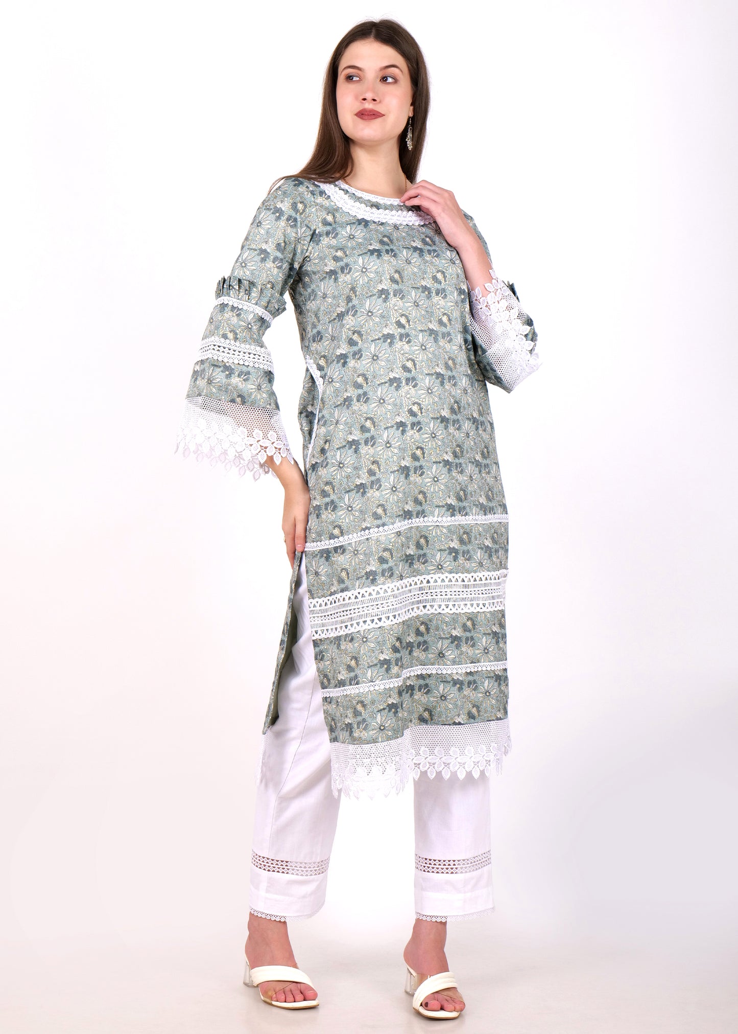 Full-length view of a woman in a green floral kurta with lace borders, styled with white straight-cut pants and heels