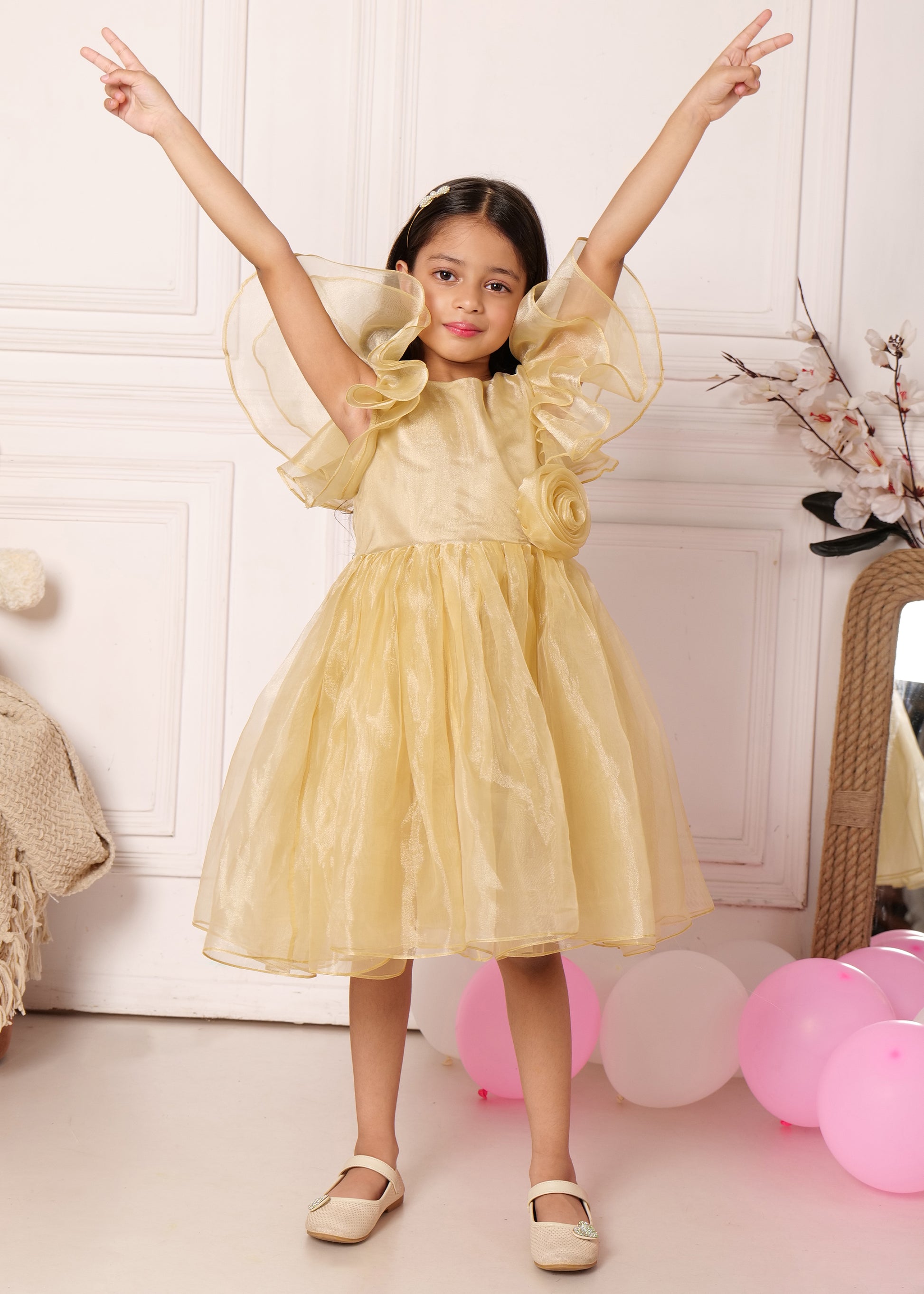 "Adorable girl twirling in a golden puff-sleeve dress, arms raised in excitement, surrounded by pastel balloons, perfect for festive occasions."