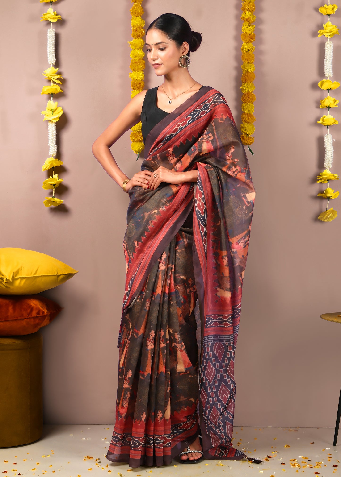 Woman posing gracefully in a red and black saree with cultural motifs and geometric border, perfect for festive or traditional events.