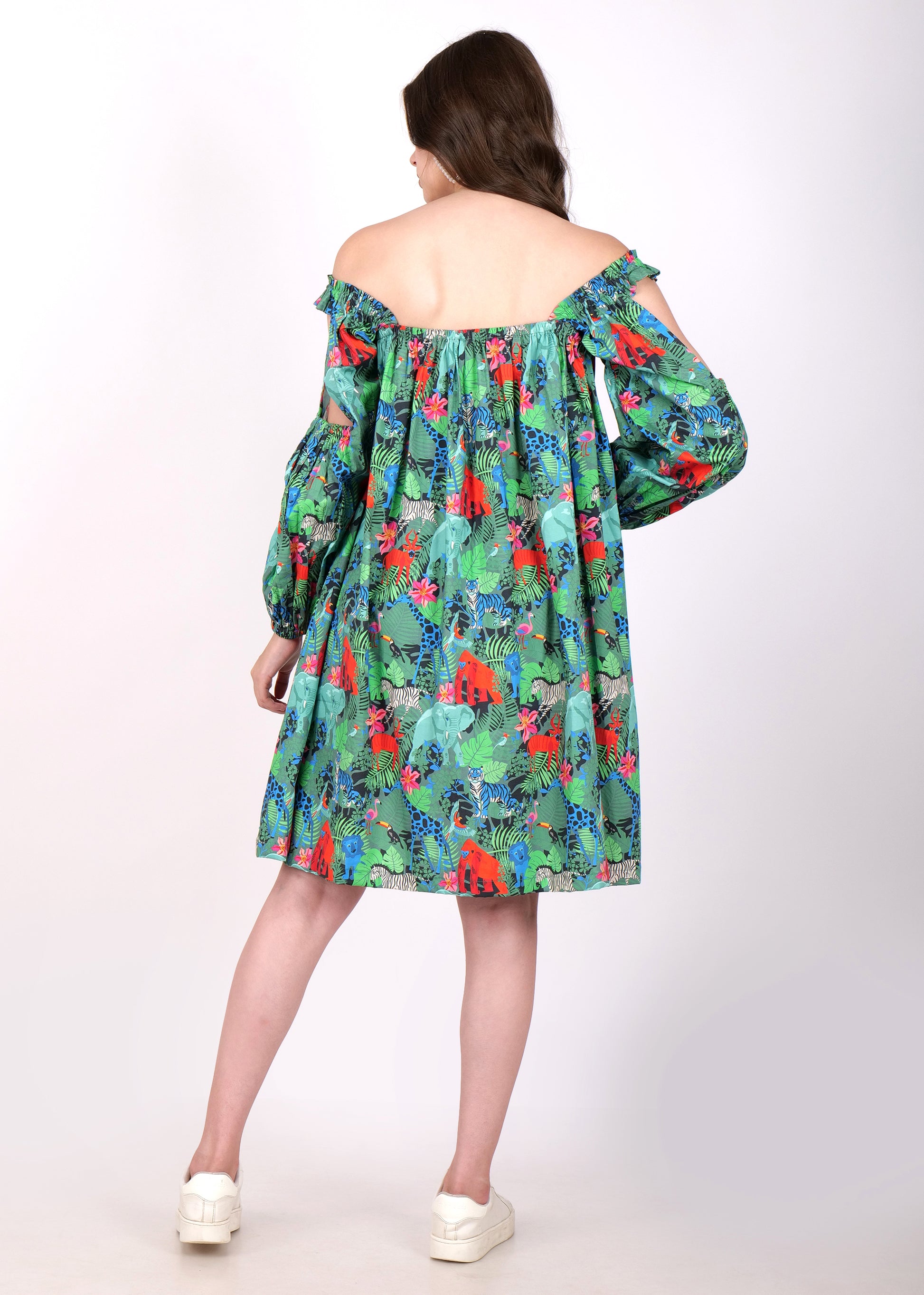 Rear view of a woman showcasing the back design of a green off-shoulder dress adorned with tropical prints