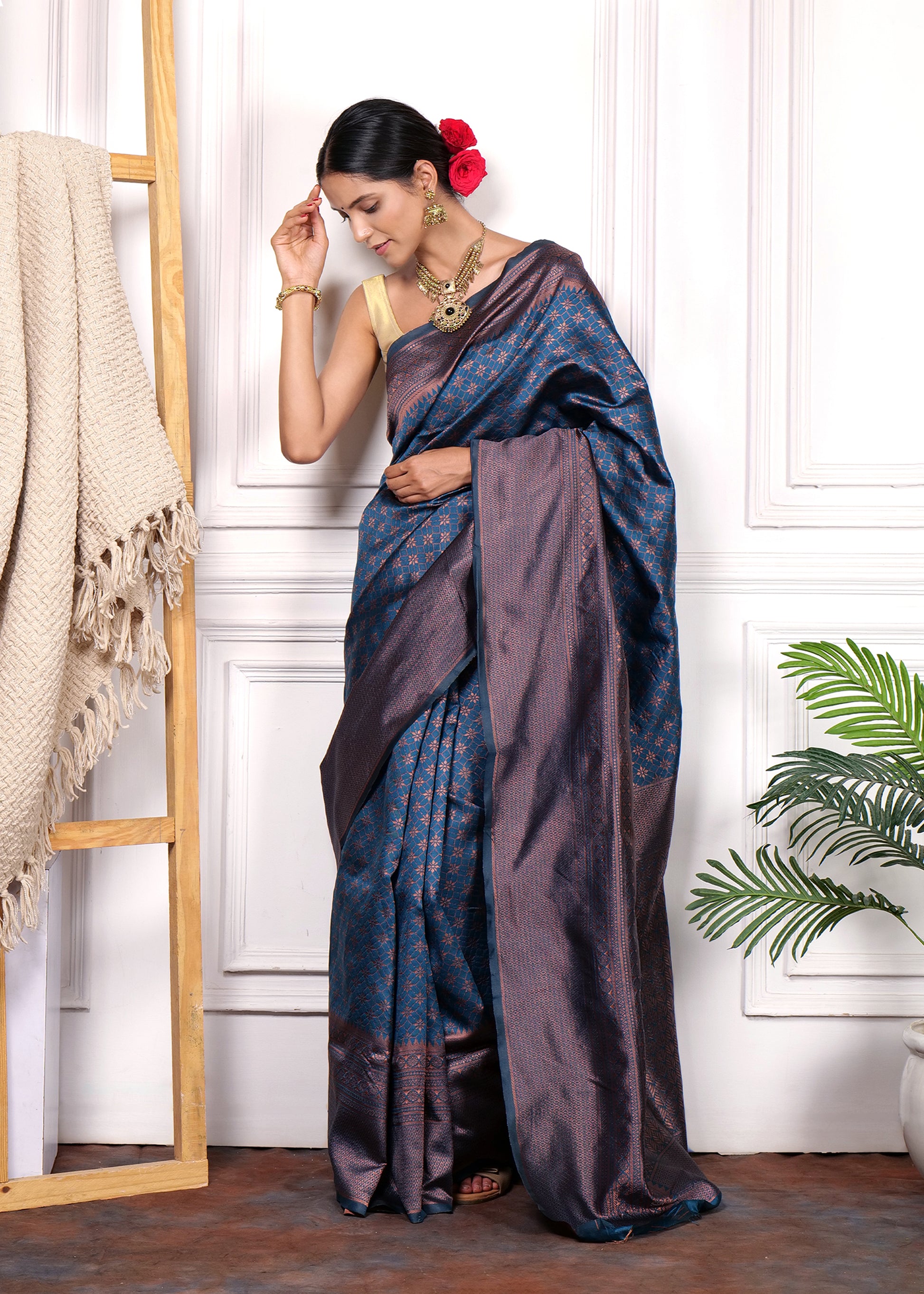 Woman draped in navy blue and copper Kanjivaram silk saree, posing gracefully with matching traditional accessories