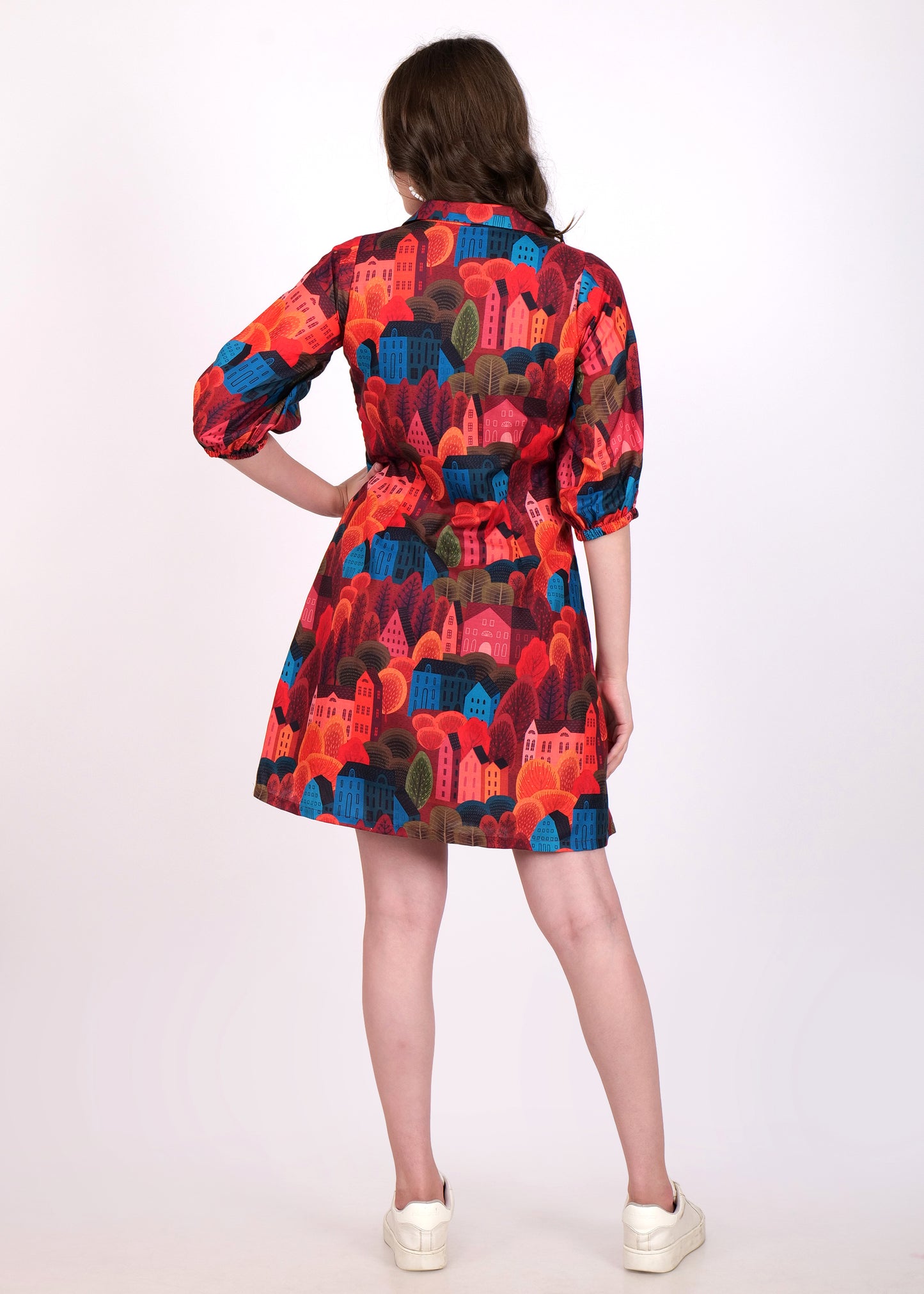 "Back view of a printed shirt dress with red, blue, and green house designs, showing the relaxed fit and three-quarter sleeves."