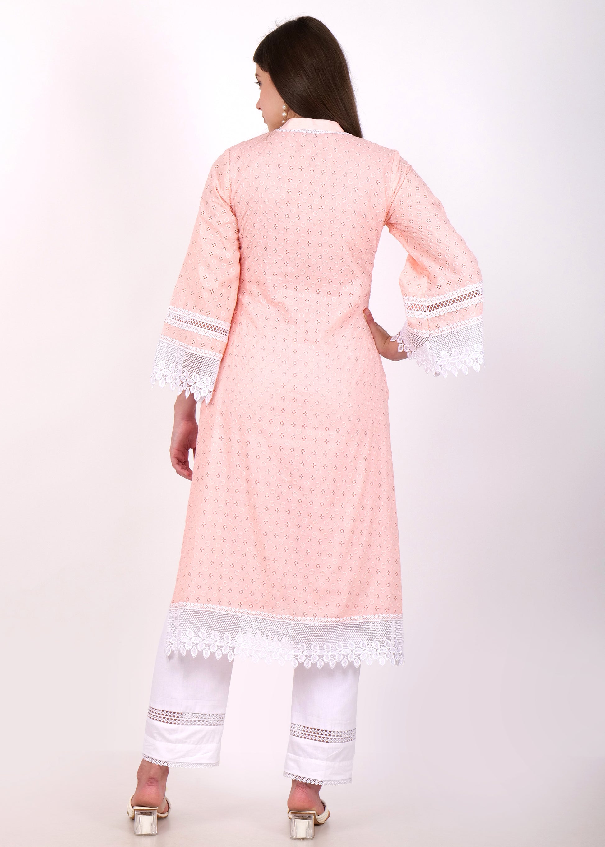 Back view of a pastel pink embroidered kurta with lace borders paired with white pants, worn by a woman