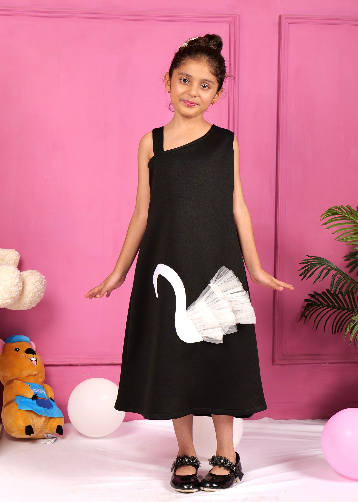 Young girl in a black swan-themed dress, smiling while showing off the unique applique design