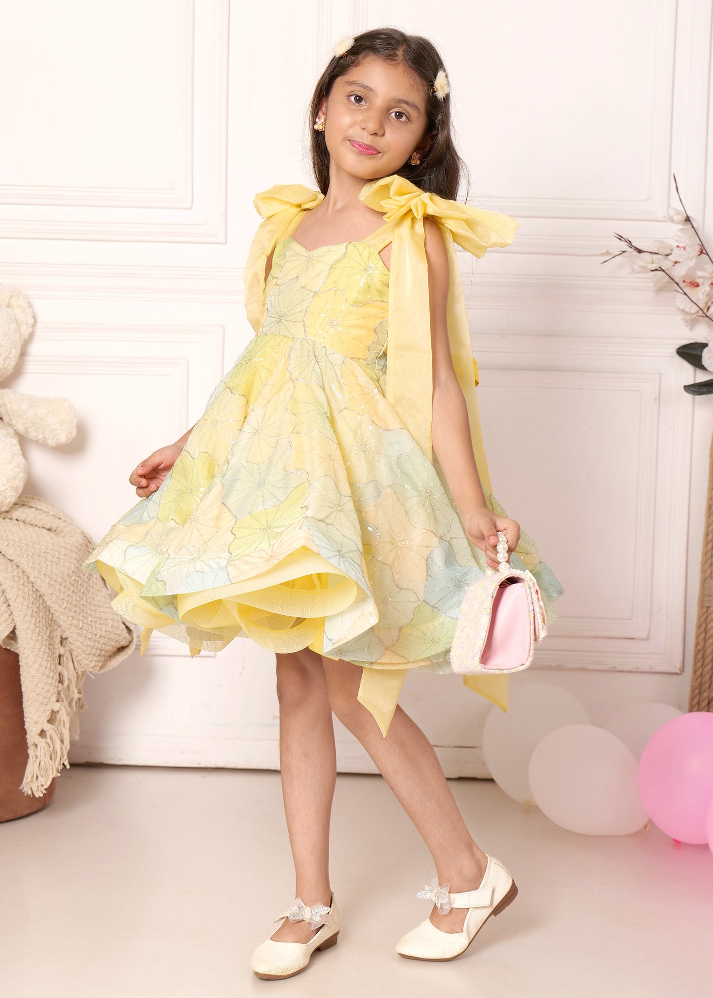 "Elegant girl twirling in a pastel yellow dress with delicate floral patterns and layered design, holding a cute handbag, perfect for special occasions."