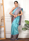 Model wearing a turquoise blue silk saree in a classic pose, styled with traditional jewelry, accentuating the royal appeal of the fabric.