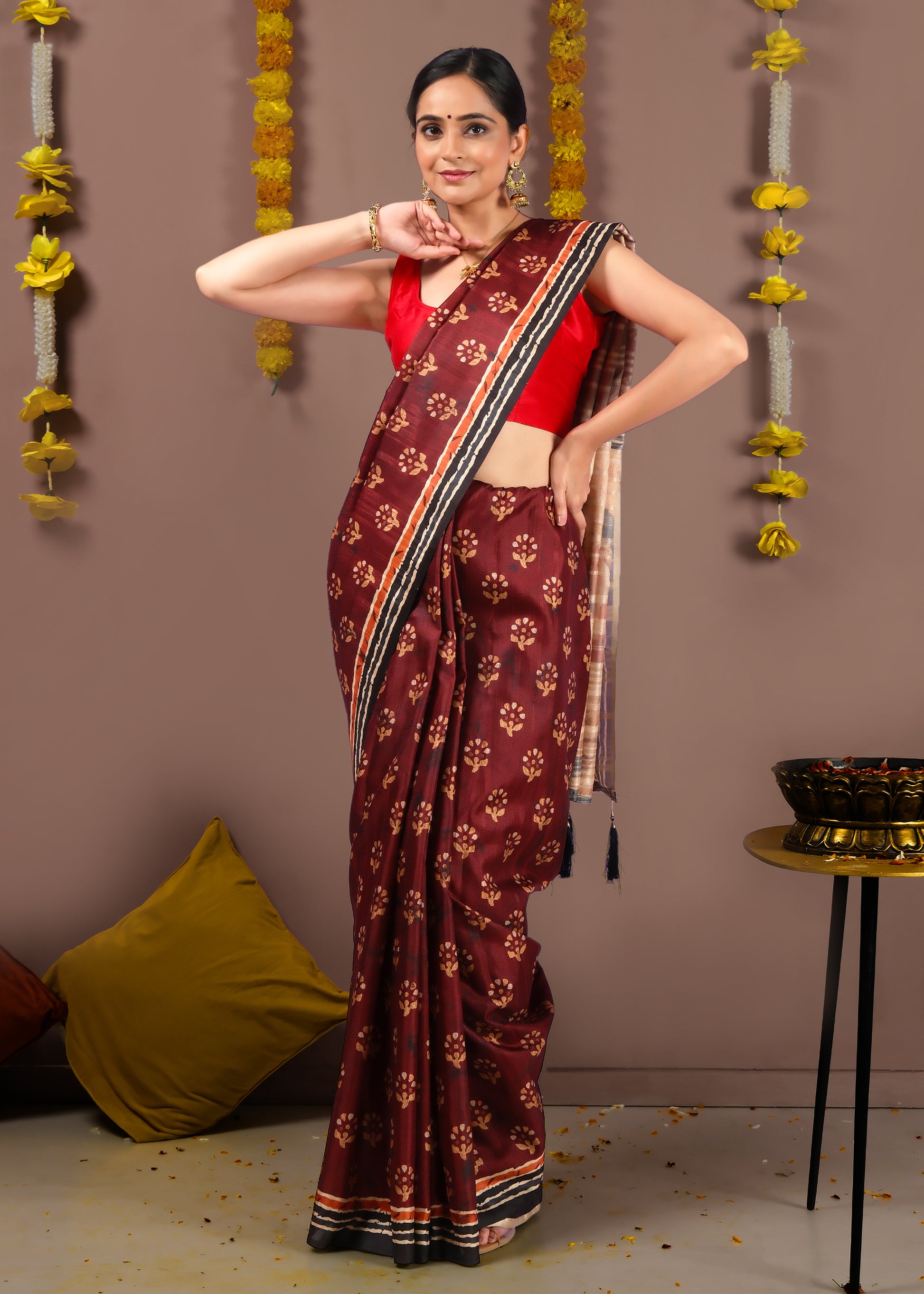 Close-up of maroon saree with golden floral motifs and intricate fabric design for traditional events