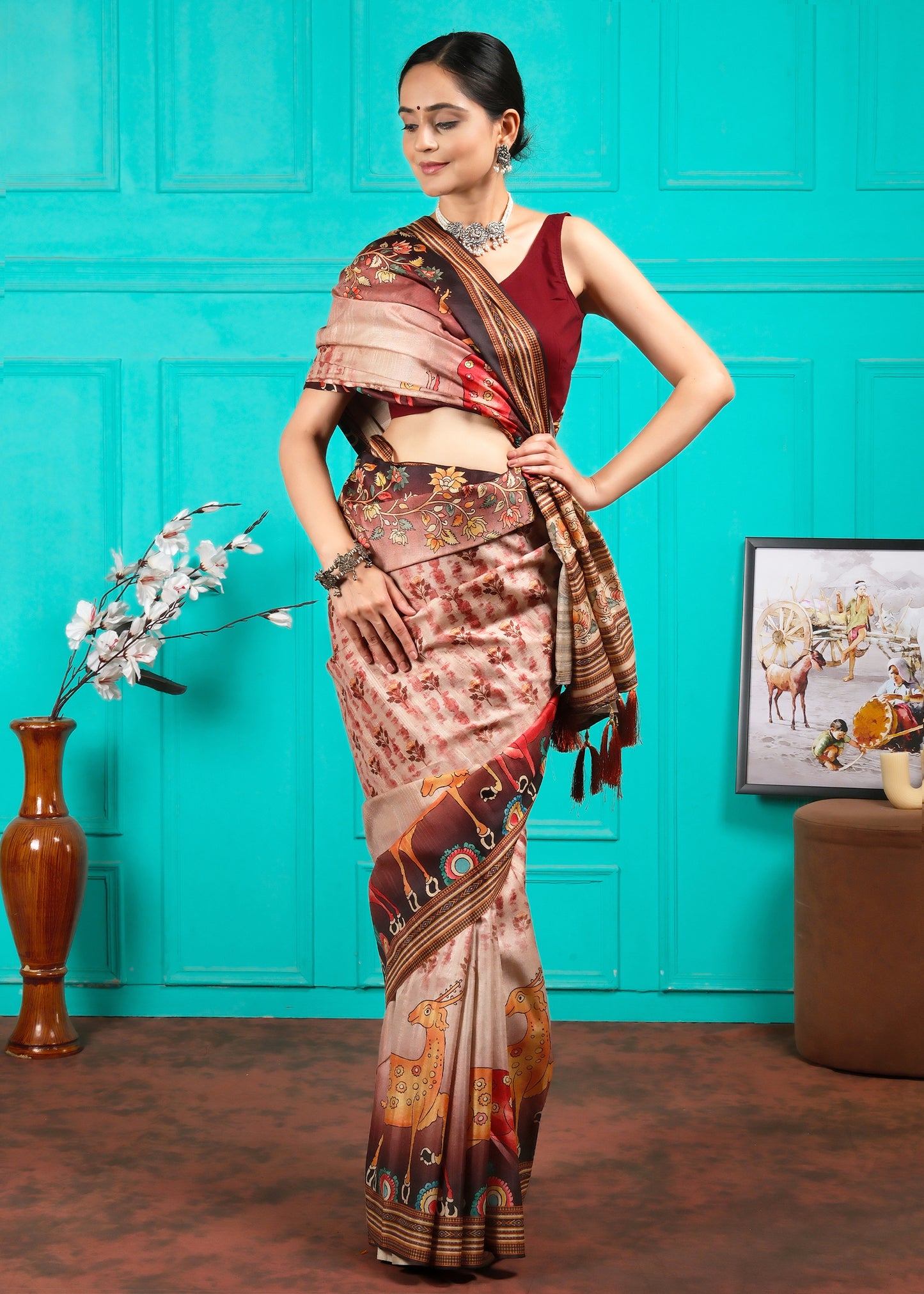 Model in traditional Indian attire posing with a beige saree featuring vibrant animal and floral motifs