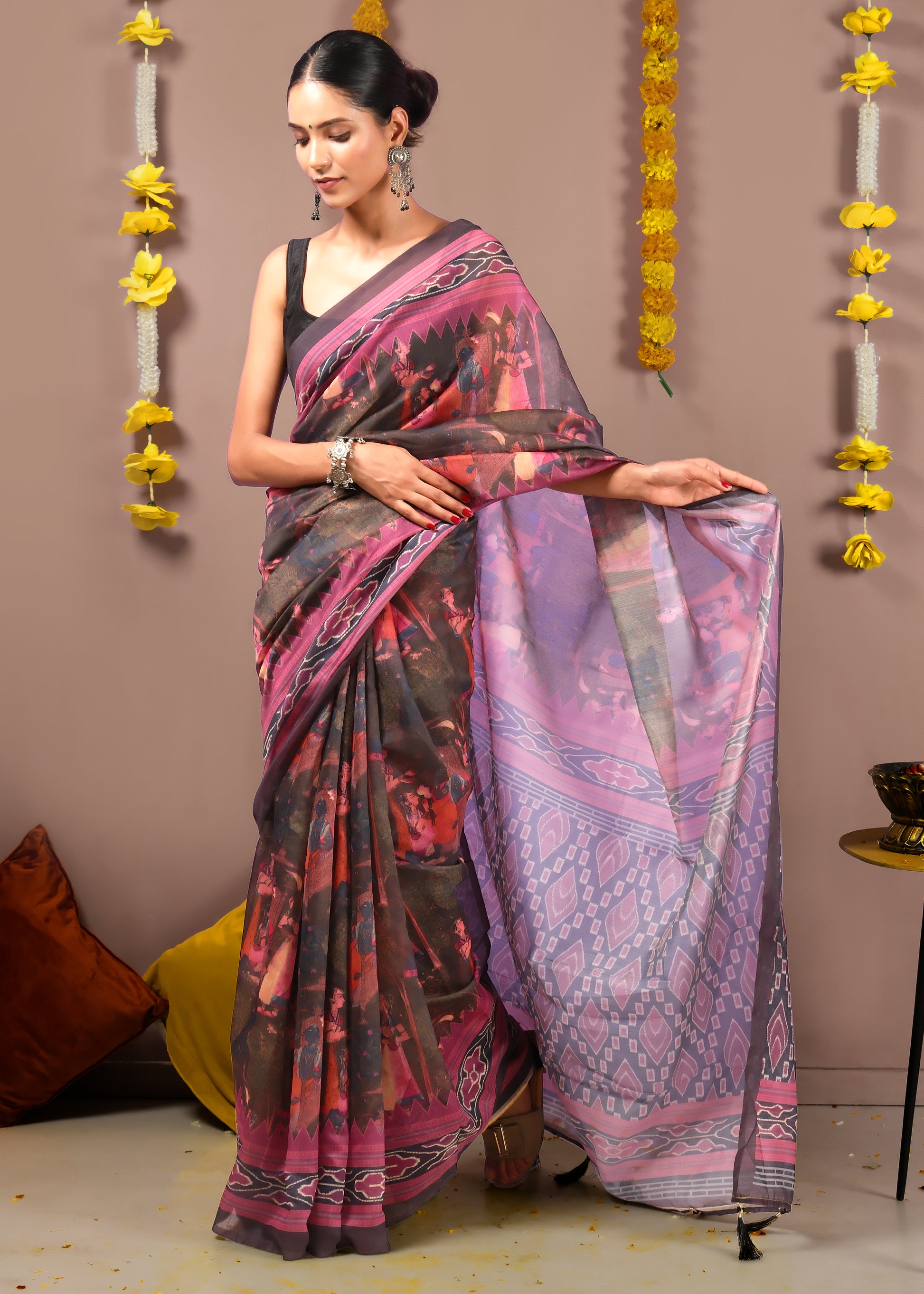 Full-length view of a woman holding the pallu of a Krishna Rasleela Ikat saree with detailed illustrations.