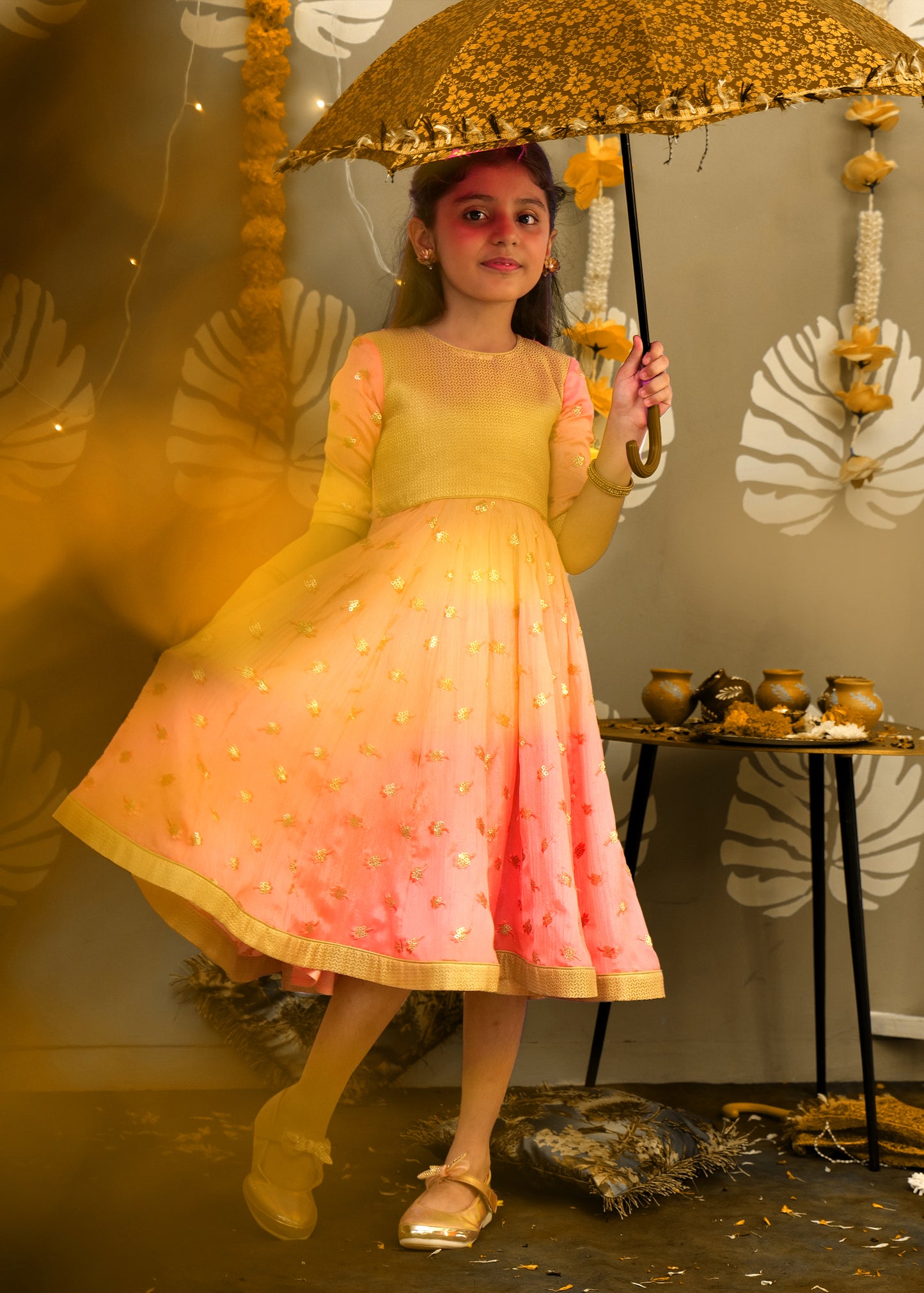 Full view of a girl in a peach and gold ethnic outfit with floral embroidery, designed for festive wear.