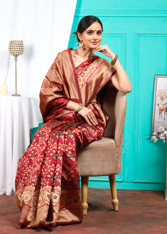 Seated woman wearing a regal red Banarasi saree with intricate floral patterns and broad golden borders