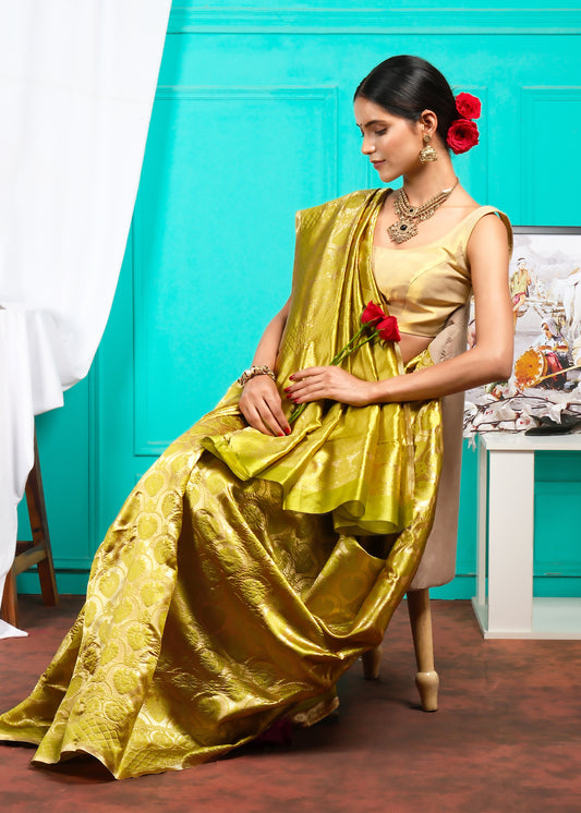 Graceful woman seated, wearing a yellow Banarasi silk saree, exuding traditional charm