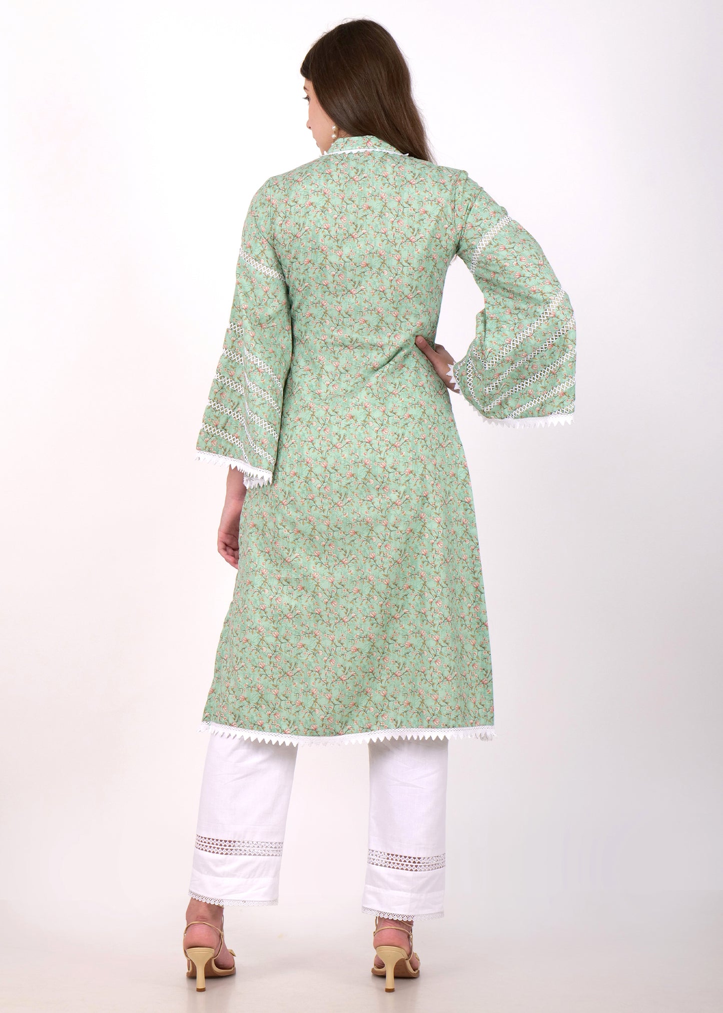 Rear view of a woman modeling a traditional green floral print kurta with lace detailing, paired with white pants