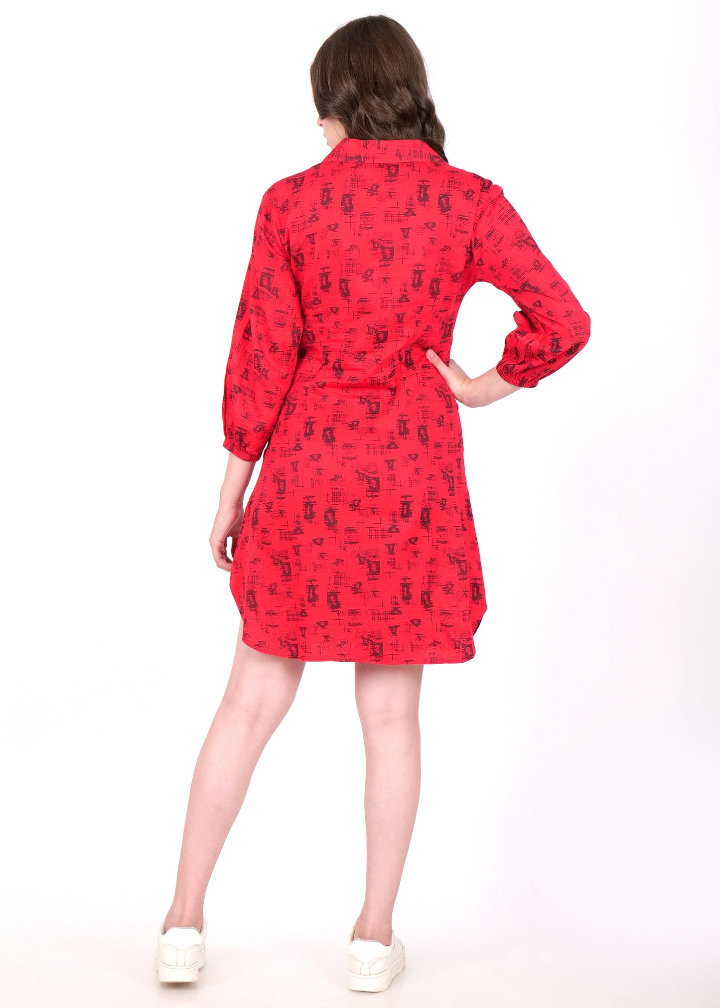 Back view of a woman wearing a red shirt dress with abstract black patterns and a belted waist, styled with casual white sneakers.