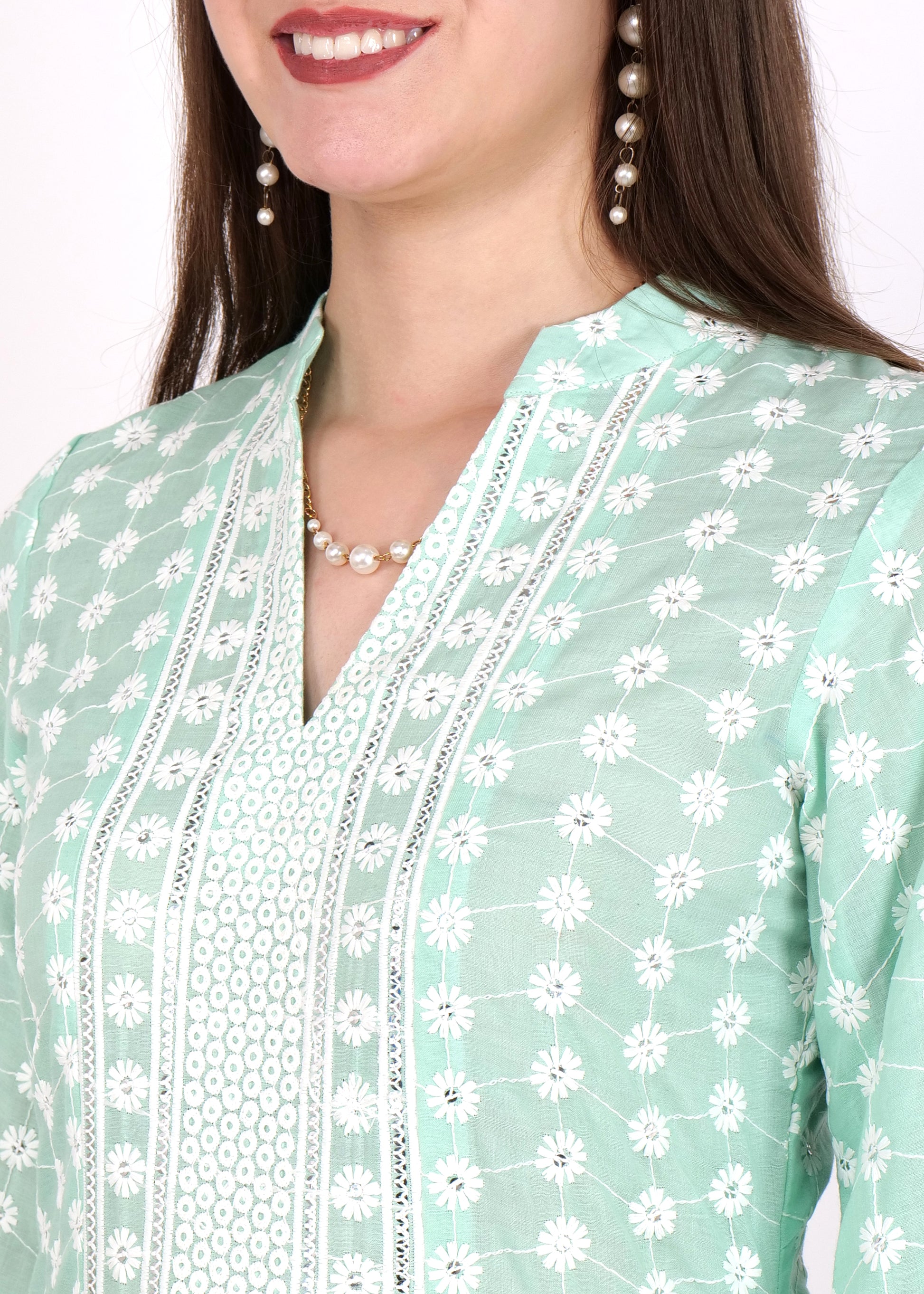 Close-up of a pink kurta's neckline, showcasing white lace embellishments and button detailing, worn with pearl drop earrings