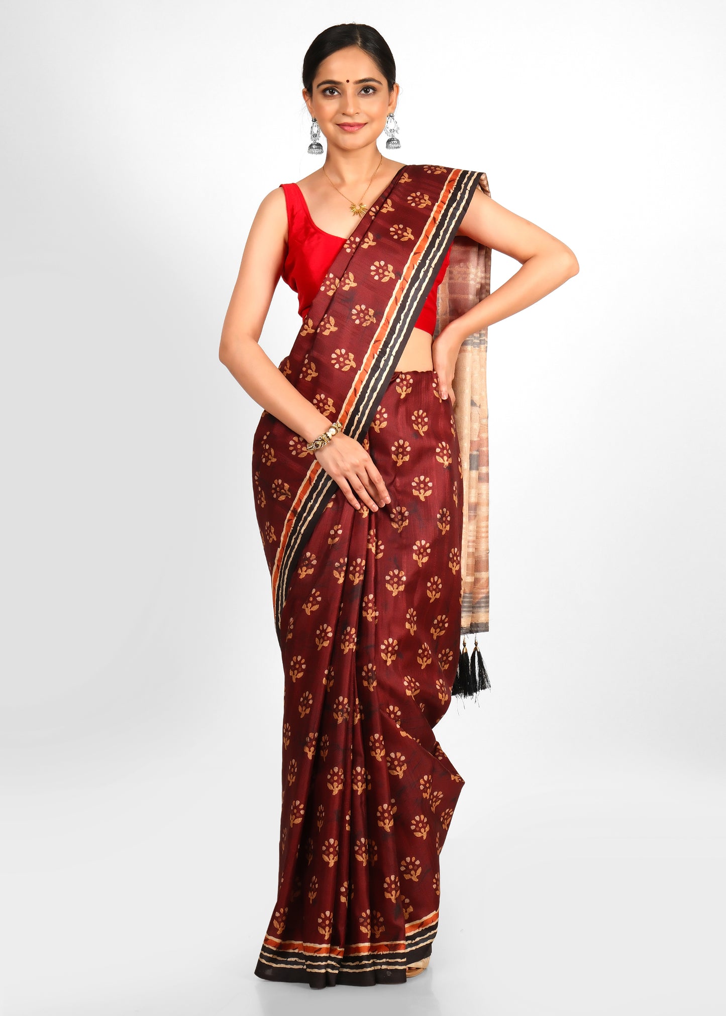 Front view of a woman wearing a maroon saree with gold floral motifs and Kalamkari pallu design.