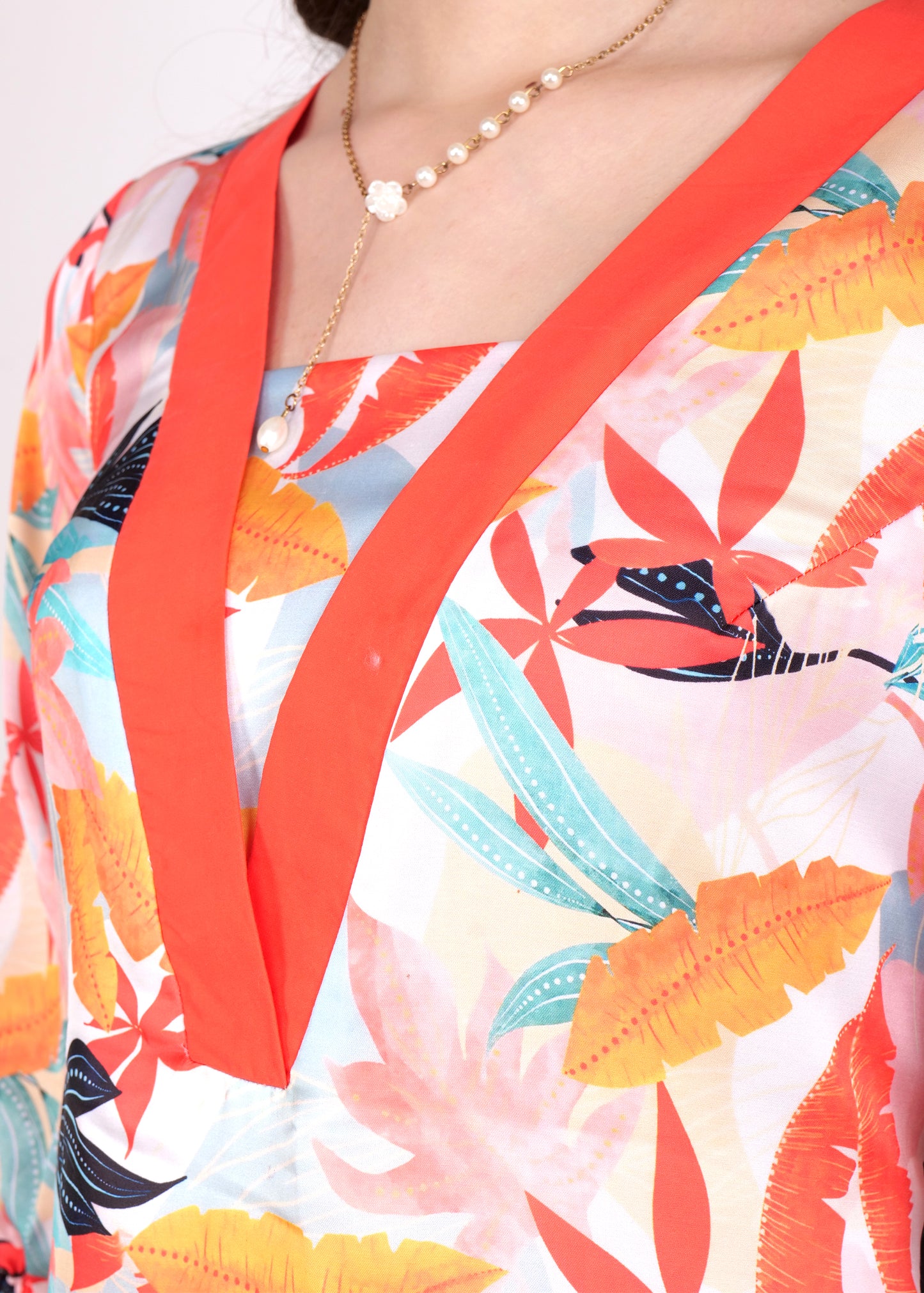 A close-up of the dress’s vibrant orange V-neck detail and the tropical floral print in bright shades of orange, yellow, and blue