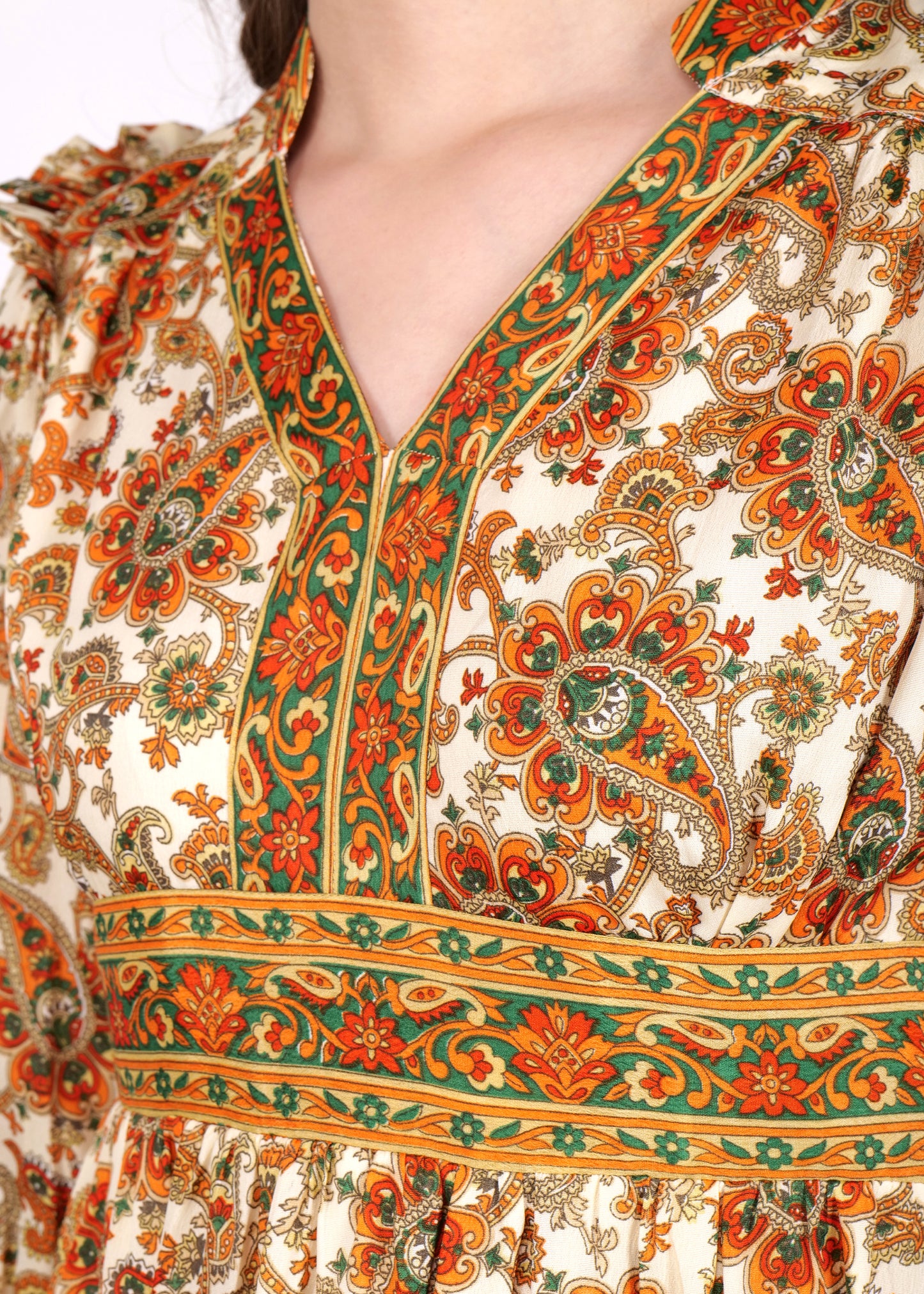 A close-up of the neckline and upper bodice, showing the intricate floral and paisley detailing in shades of orange, green, and cream