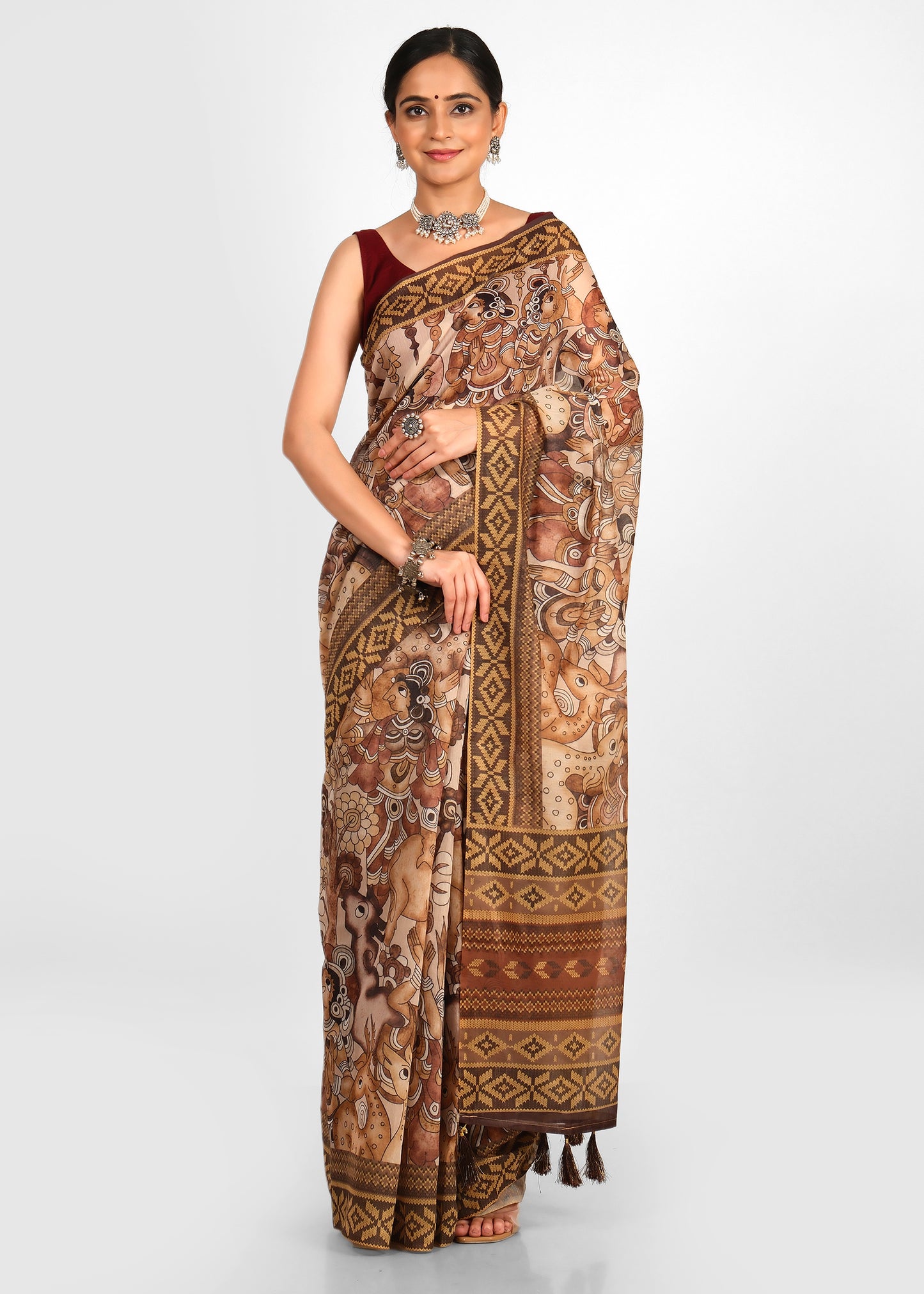 woman wearing a hand-printed saree with mythological motifs, detailed with tassels on the pallu, exuding traditional charm