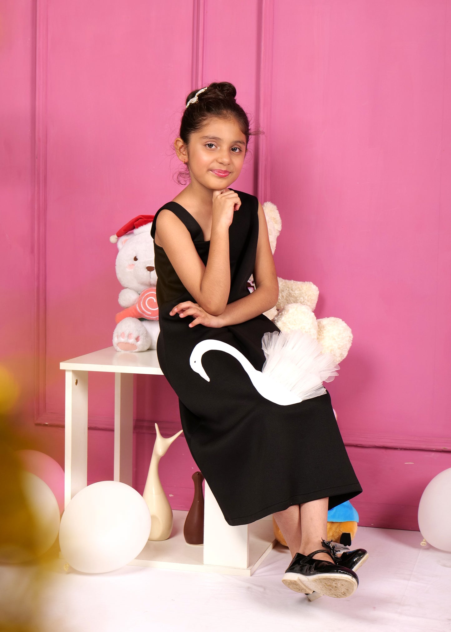 Young girl in a black swan-themed dress, smiling while showing off the unique applique design