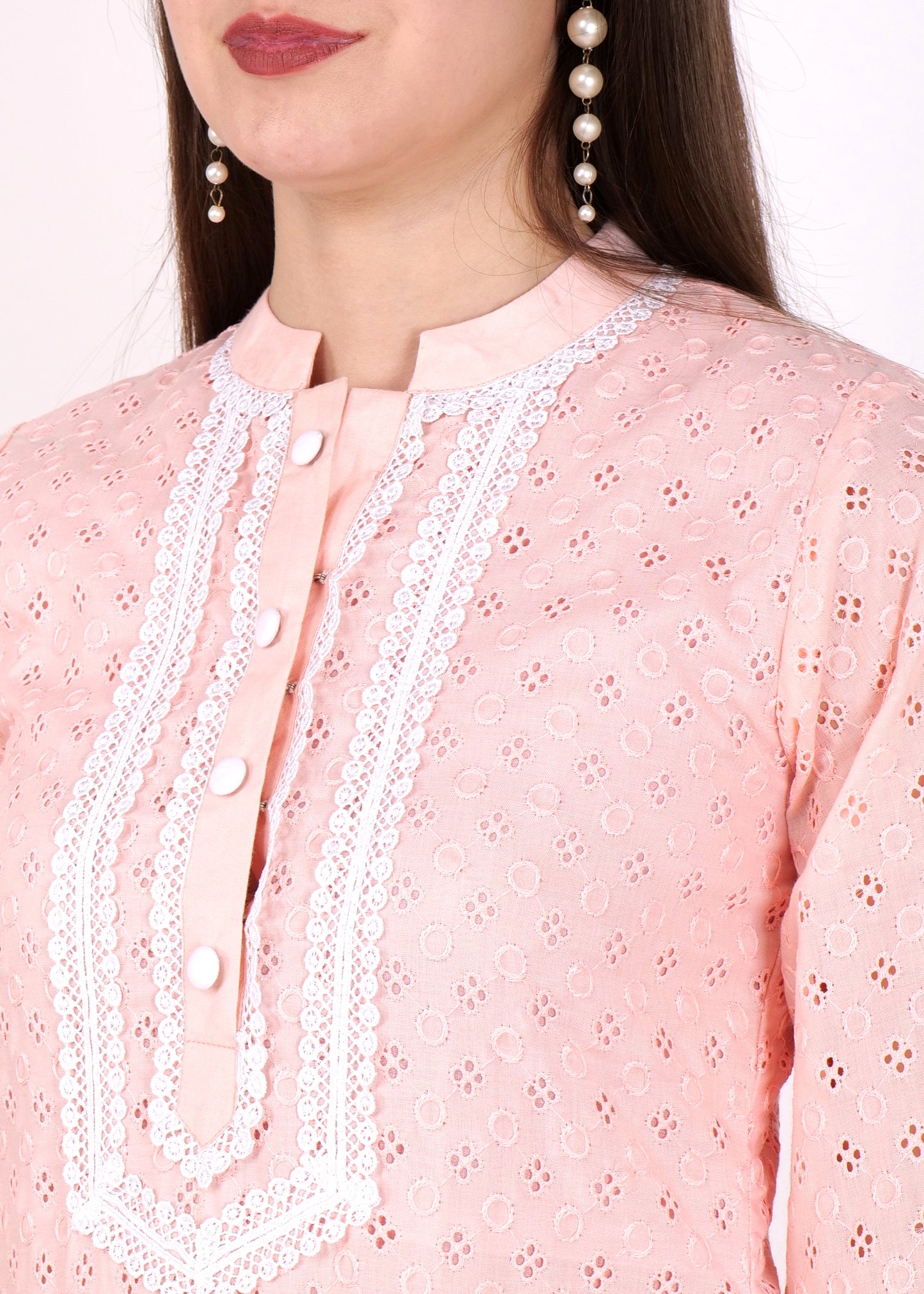 Close-up of a pastel pink kurta with lace embroidery around the neckline, showcasing pearl earrings and button details