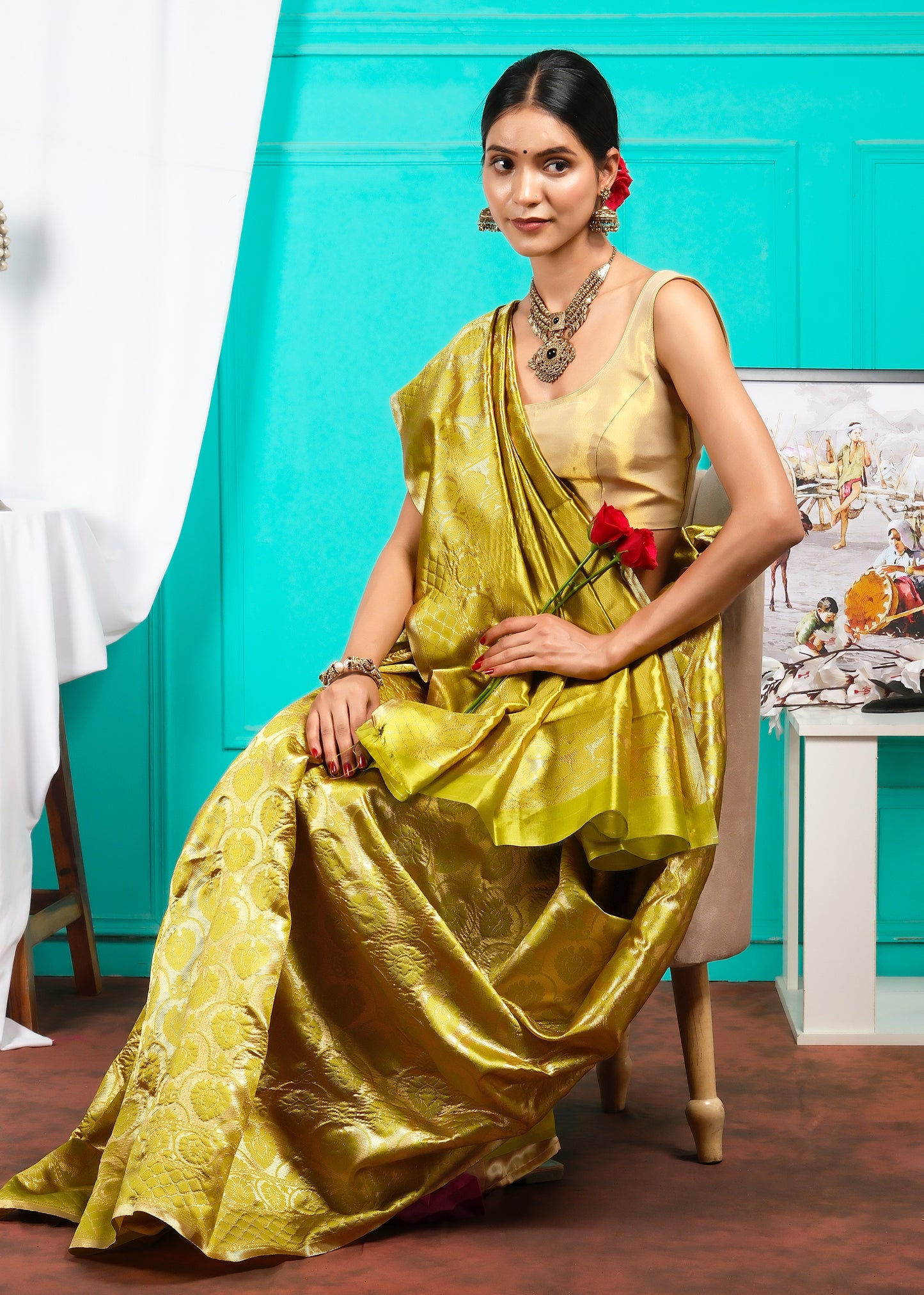 Model in a yellow Banarasi silk saree, sitting elegantly, showcasing intricate golden patterns