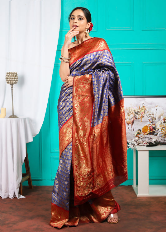 Model wearing a classic Banarasi saree in blue and red, embellished with luxurious golden embroidery, styled for a festive occasion