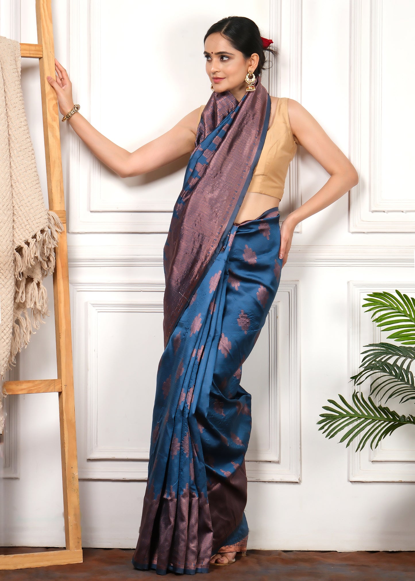 Elegant pose of a model in royal blue silk saree with intricate copper zari work, styled with traditional jewelry