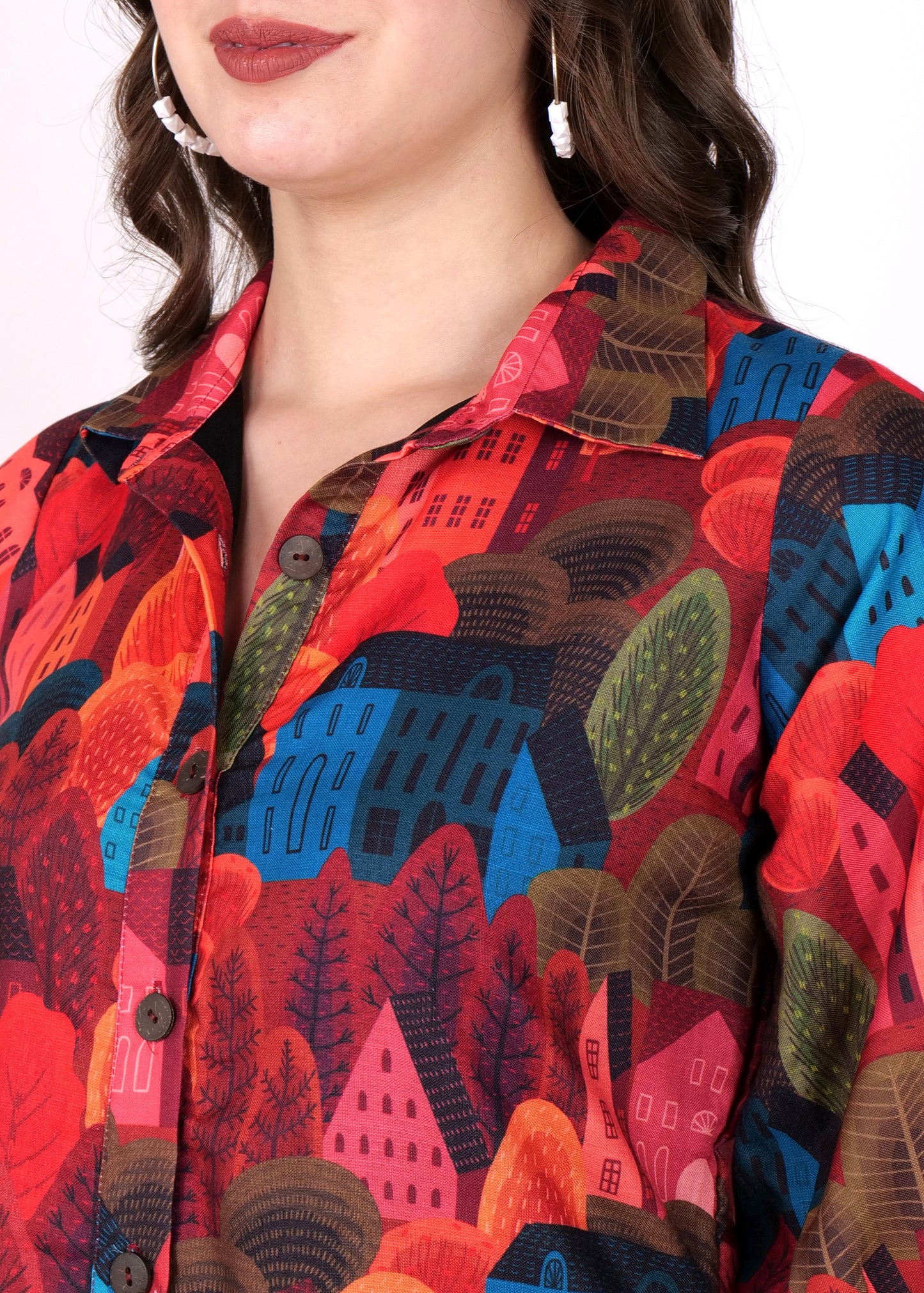 "Close-up of a multicolored shirt dress featuring a bold house print in shades of red, blue, and orange, with a collared button-down design."