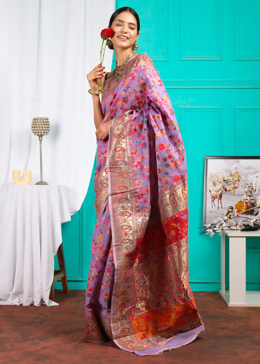 Woman posing gracefully in a lavender floral saree, featuring a rich red and gold pallu, with intricate detailing and traditional accessories, holding a red rose