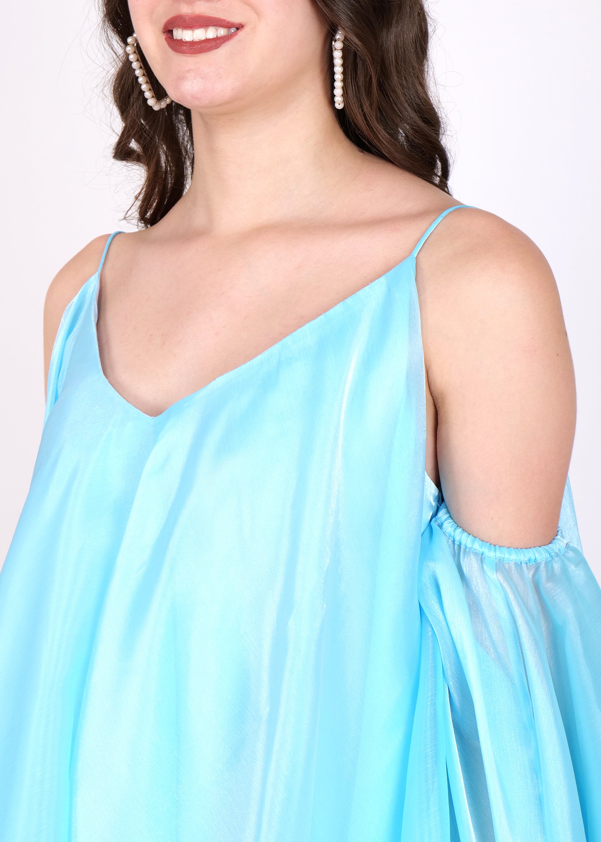 A close-up view of the dress's V-neckline with pearl earrings, highlighting the model's accessories and the dress’s smooth fabric.