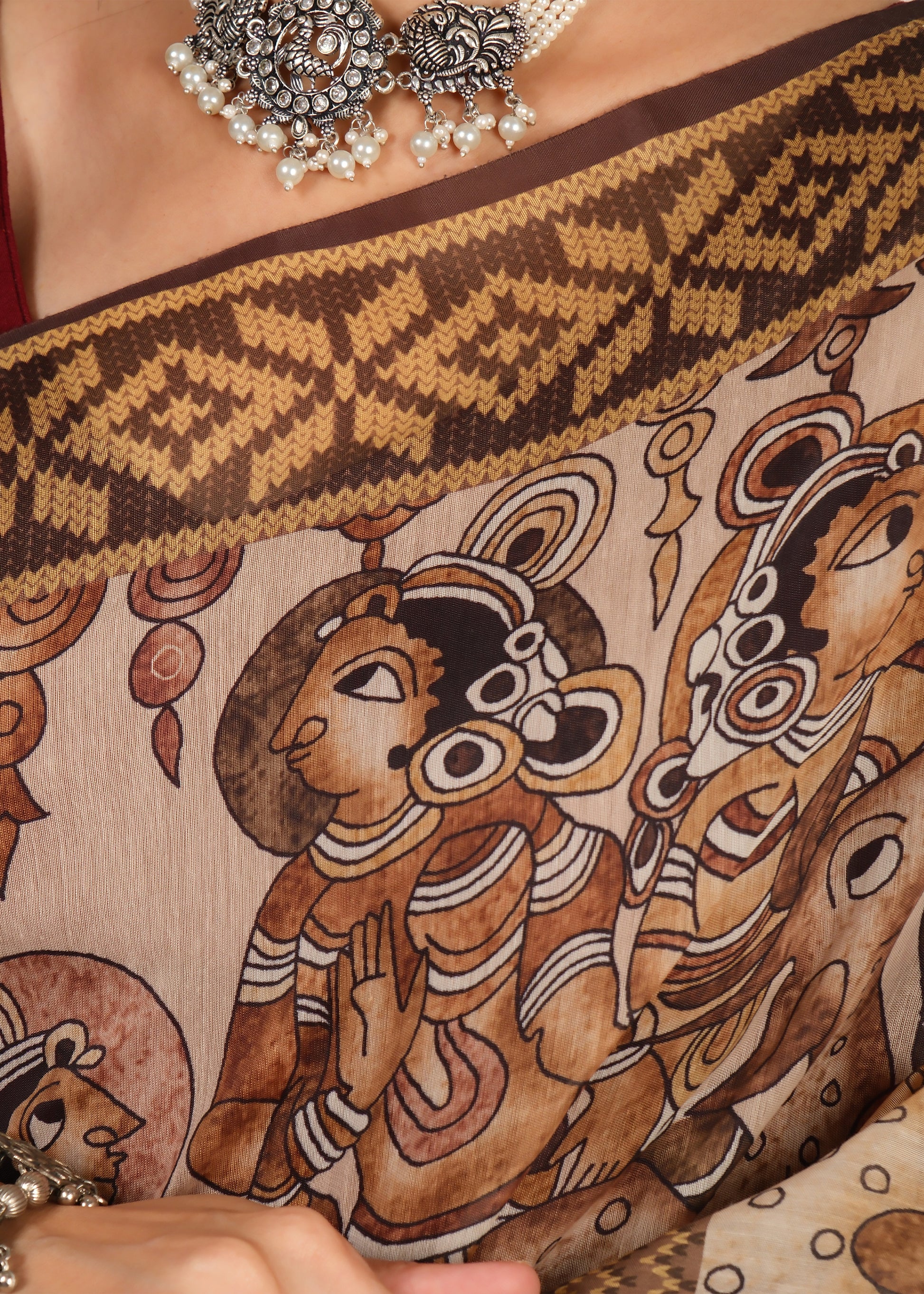 Close-up of a hand-painted saree with intricate designs depicting deities, complemented with a vintage-style necklace