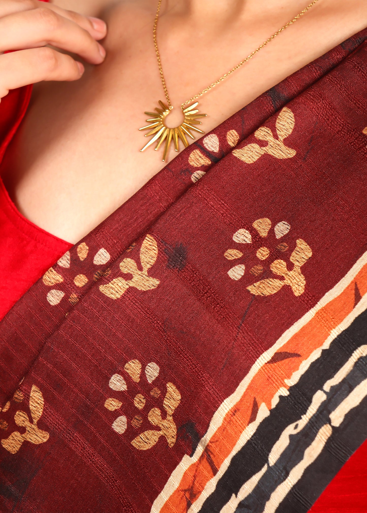 Close-up of maroon saree with gold floral motifs and intricate Kalamkari artwork on the pallu.