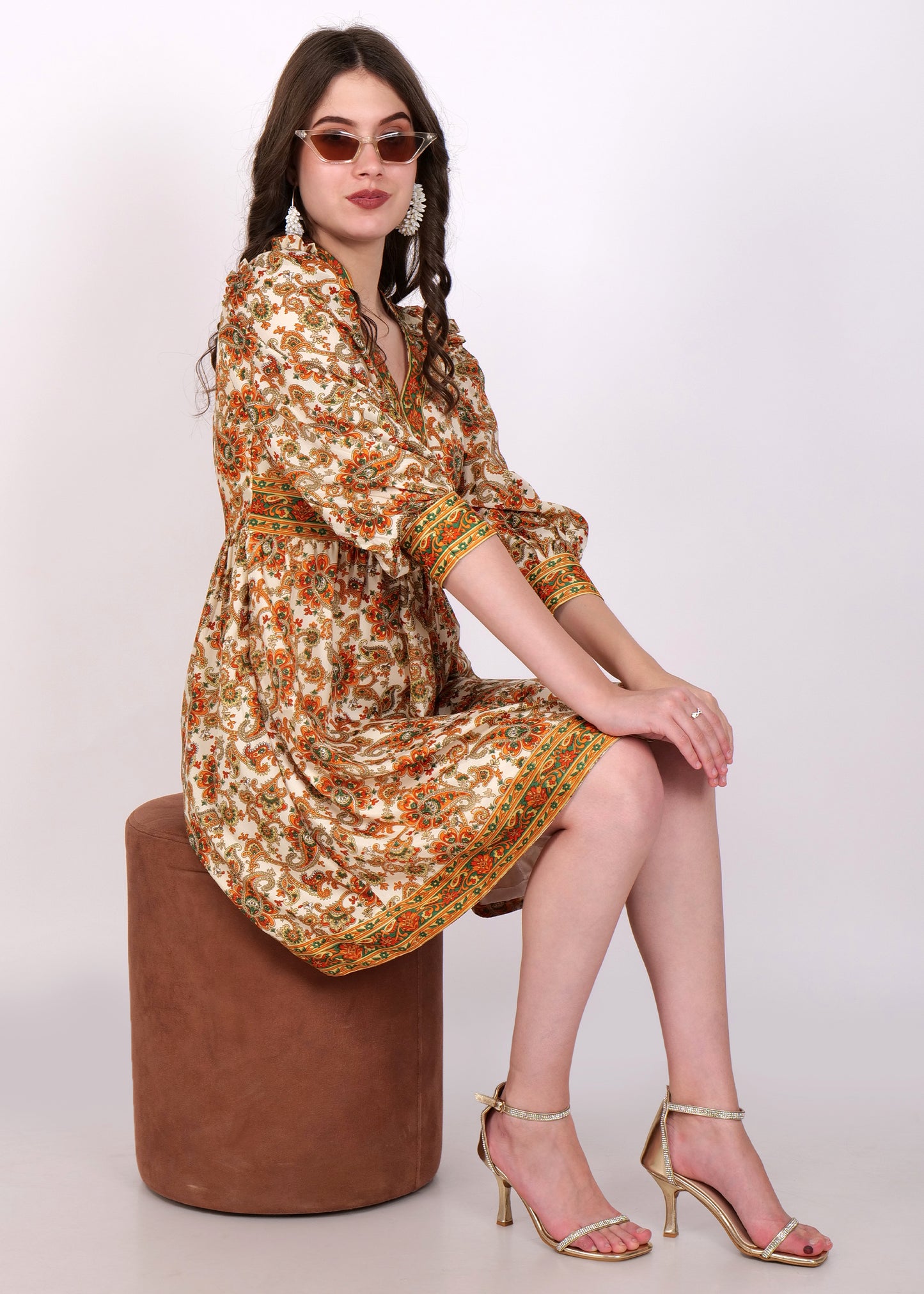 The woman seated while wearing the floral boho dress, with a relaxed pose, exuding vintage charm in the beautifully patterned outfit.