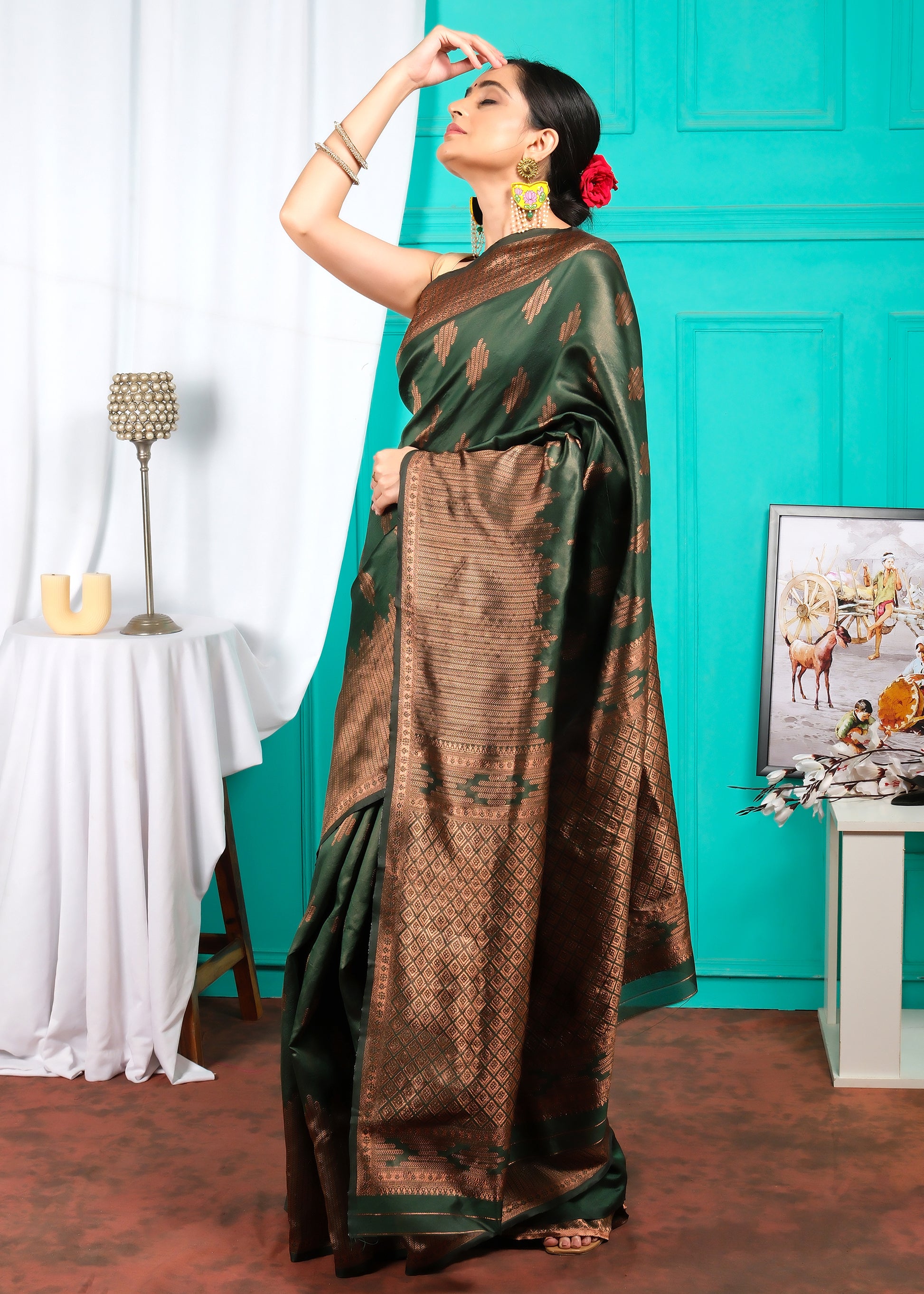 Woman striking a pose in a luxurious green and brown silk saree with gold zari detailing