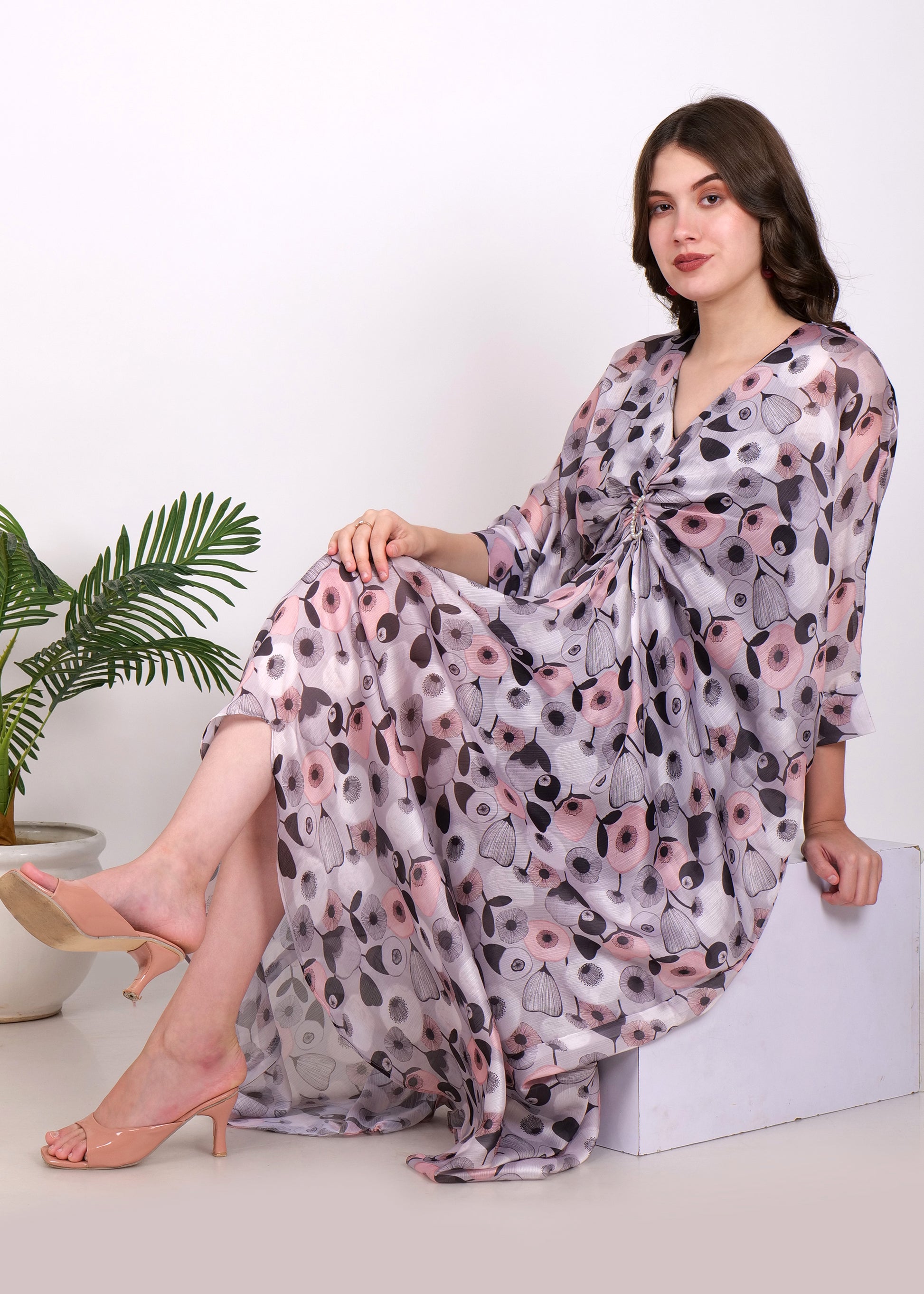 The woman seated gracefully, wearing the floral kaftan, with soft fabric draped elegantly around her for a relaxed yet stylish look.