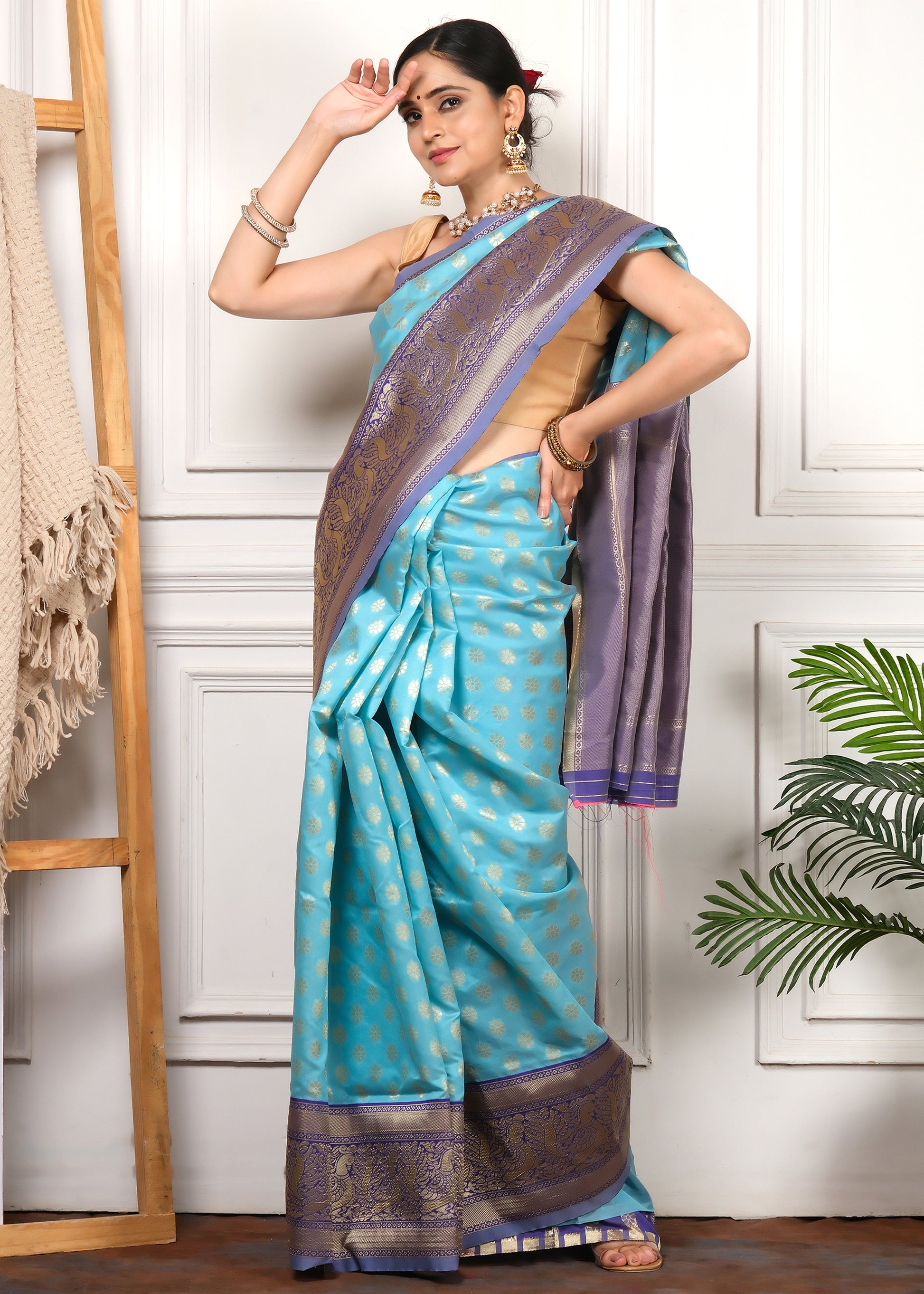 Traditional turquoise blue silk saree adorned with purple and gold motifs, styled with ethnic jewelry, perfect for weddings and festive occasions.