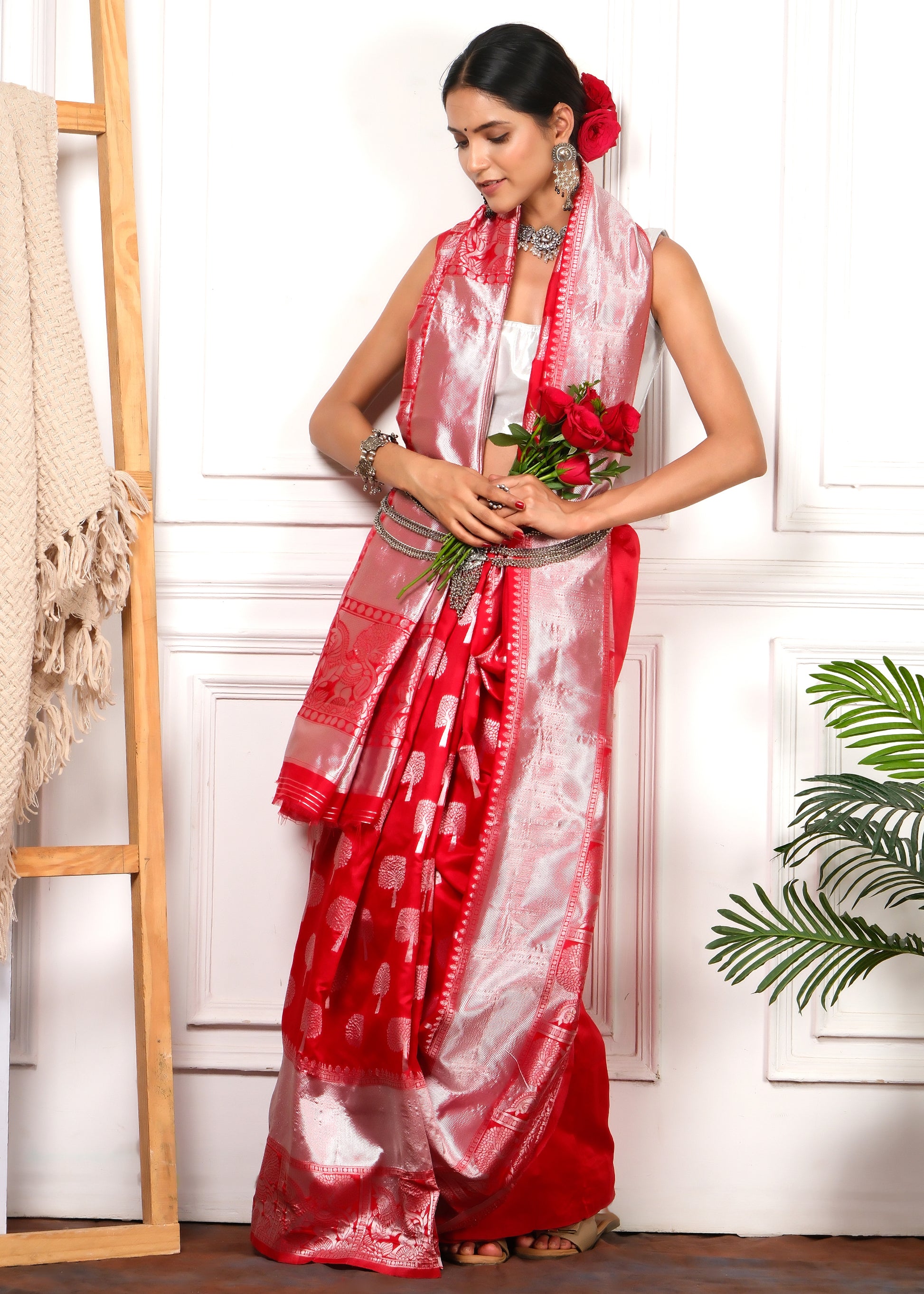 A model in a vibrant red and silver saree holding red roses, embodying a romantic and elegant Indian wedding aesthetic