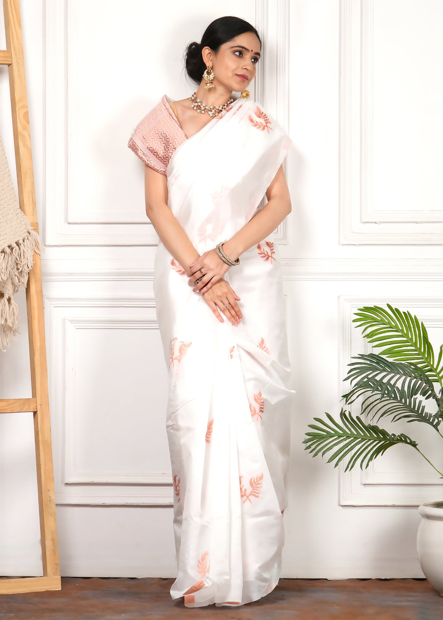 A poised look featuring a white silk saree with handwoven motifs in orange, worn with a statement blouse and ethnic jewelry