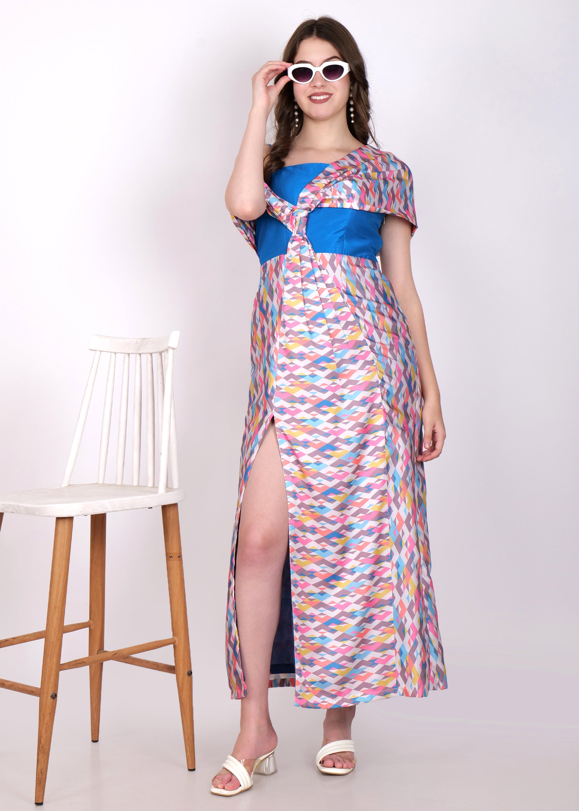 Model posing in a colorful geometric print off-shoulder dress with white heels and cat-eye sunglasses.