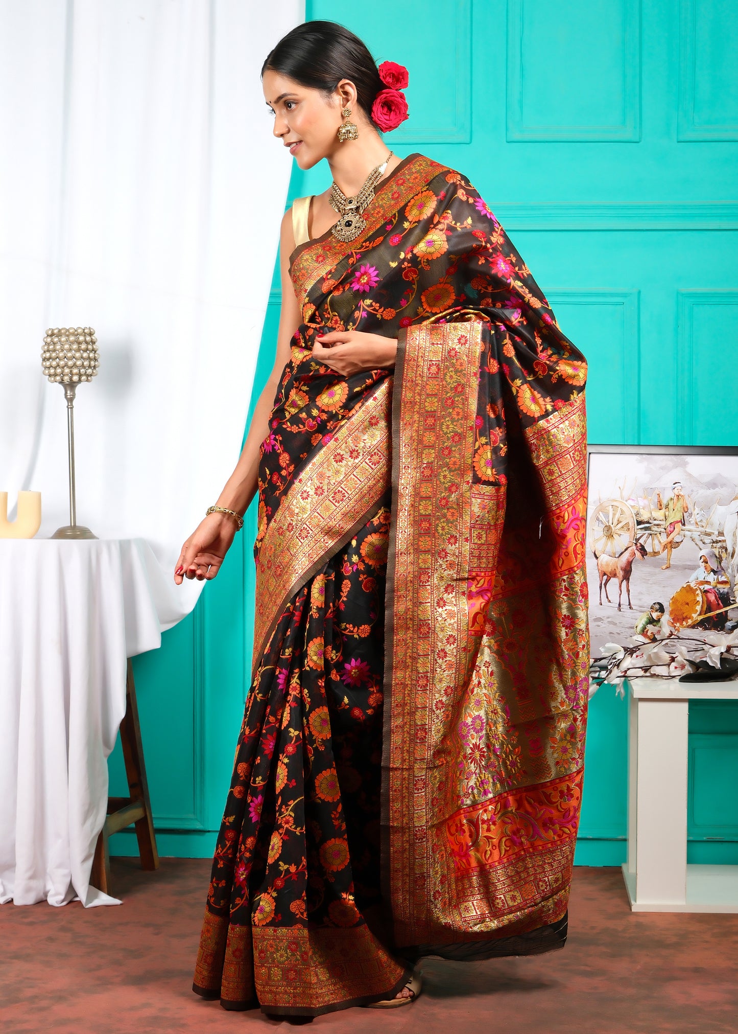 Standing model in a luxurious black Banarasi silk saree with vibrant floral designs and golden border, capturing a regal essence